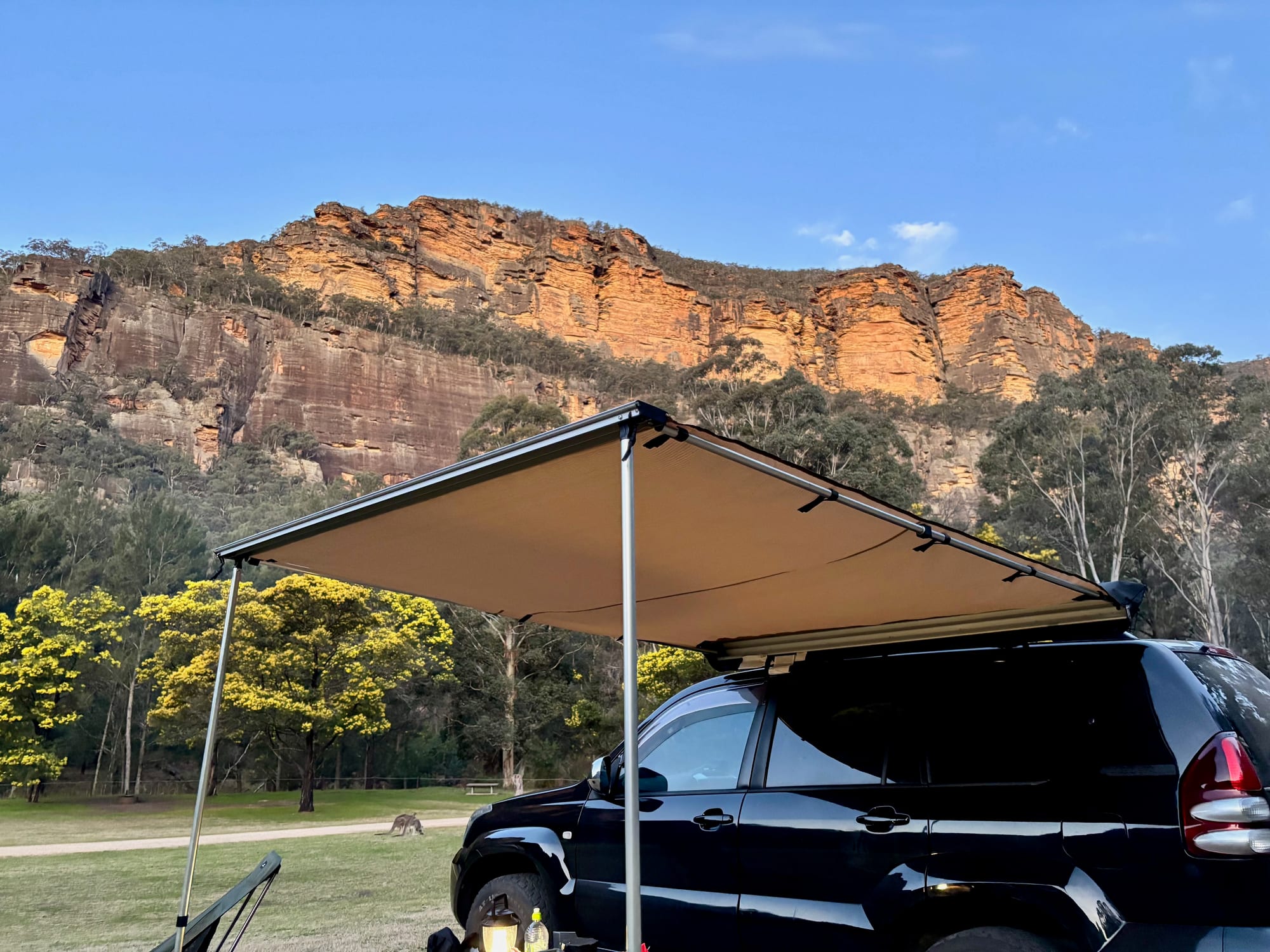 Our 4WD with the awning out at camp, below a line of sandstone cliffs