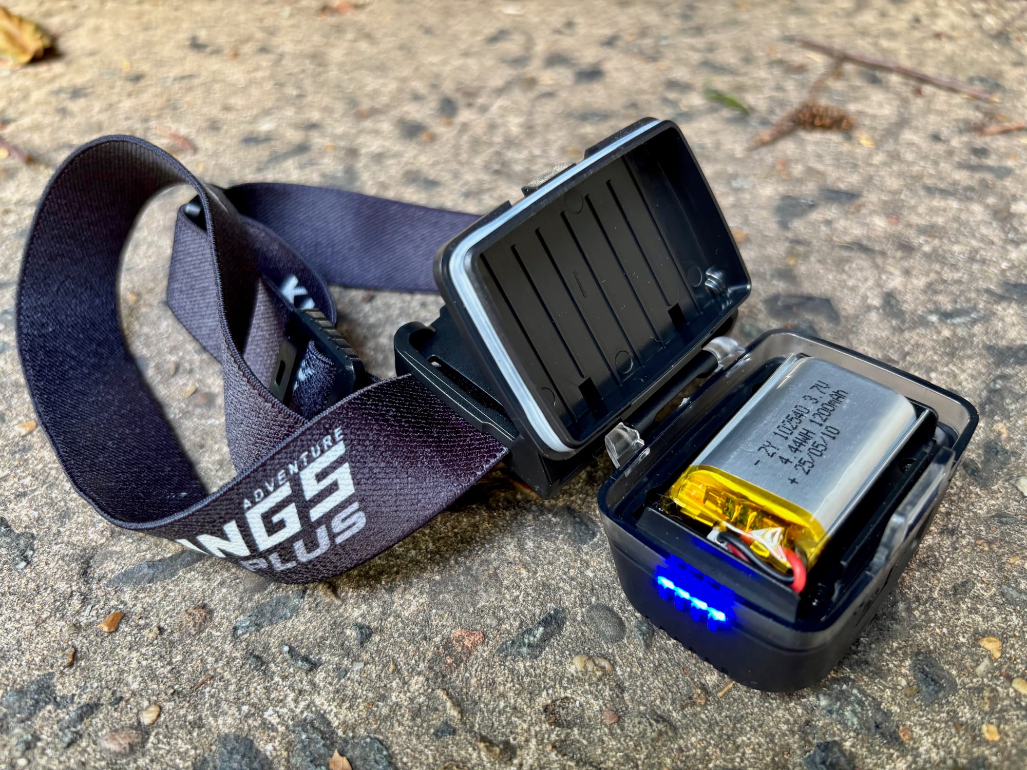 The back of the Adventure Kings head torch opened, showing the 1200 mAh battery and four blue battery-level lights