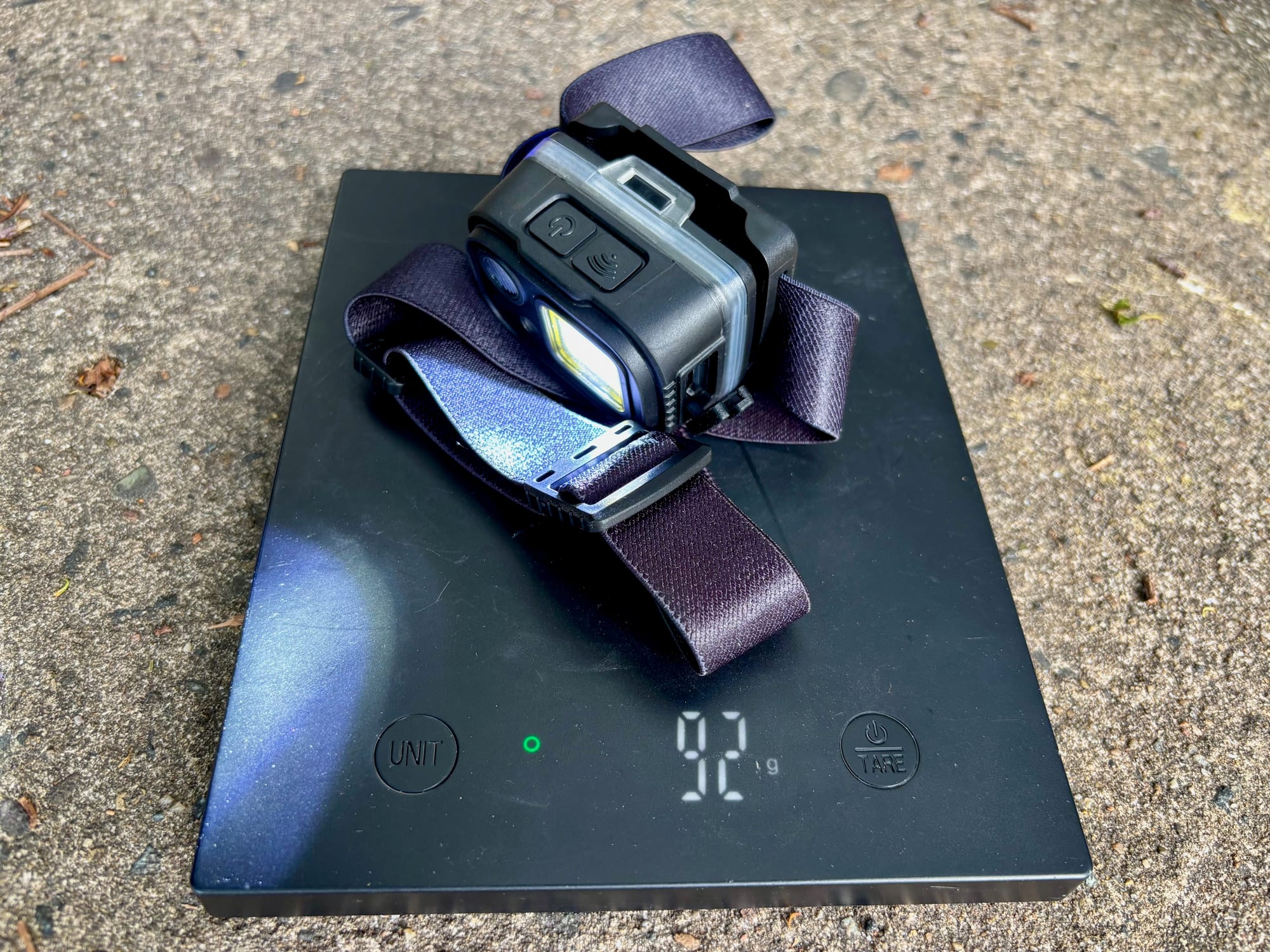 The Adventure Kings head torch on a kitchen scale showing 92 g