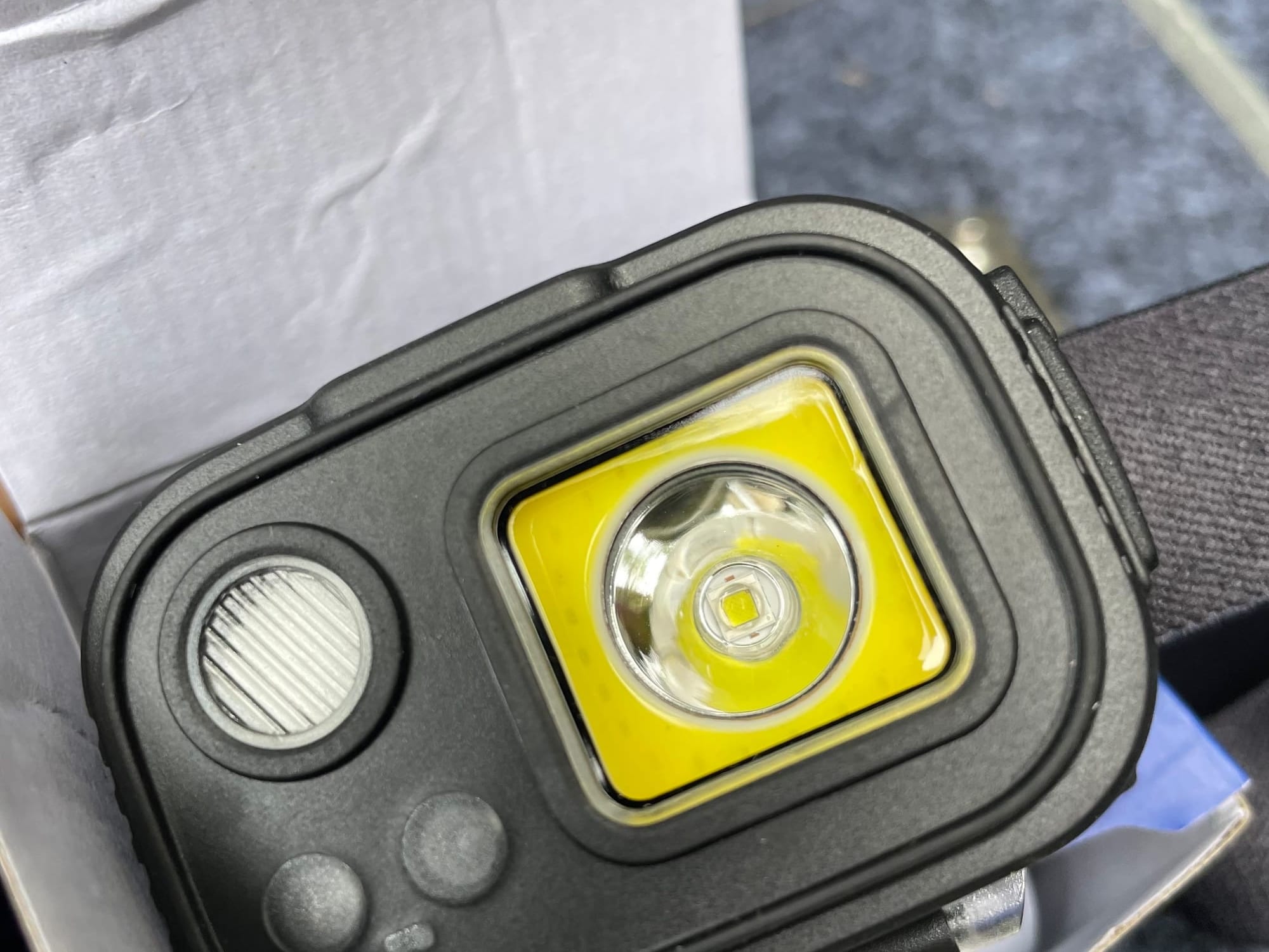 Close-up of the front of the Adventure Kings head torch: the square spot and flood light, the round red light and the two sensor windows