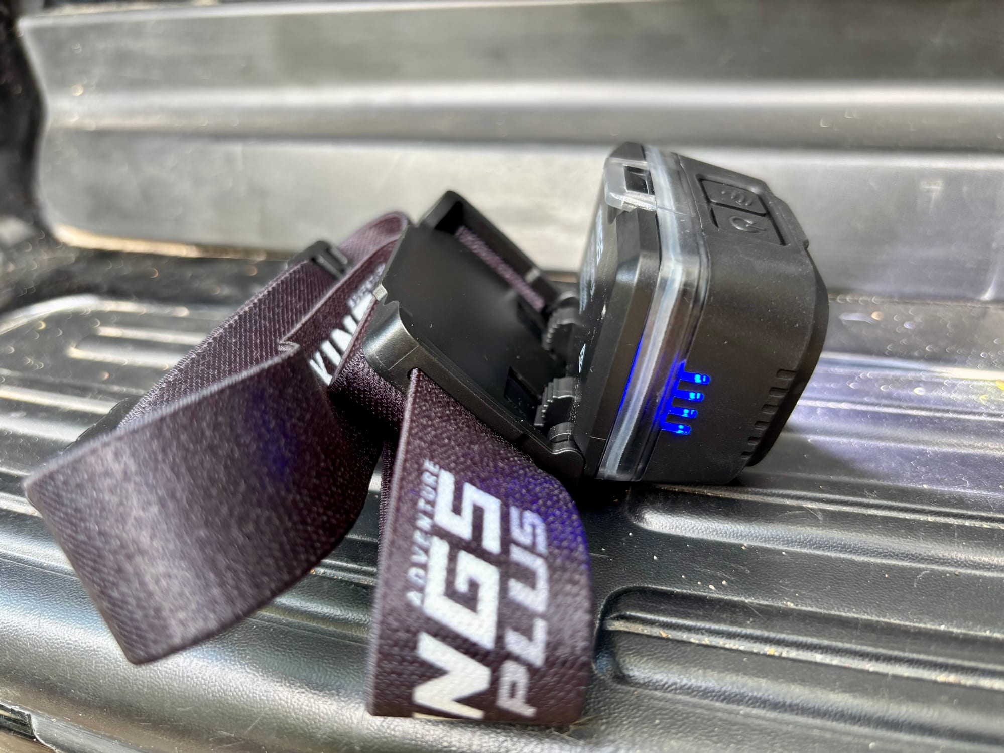 The Adventure Kings head torch tilted forward on its hinged bracket, with the blue battery lights on