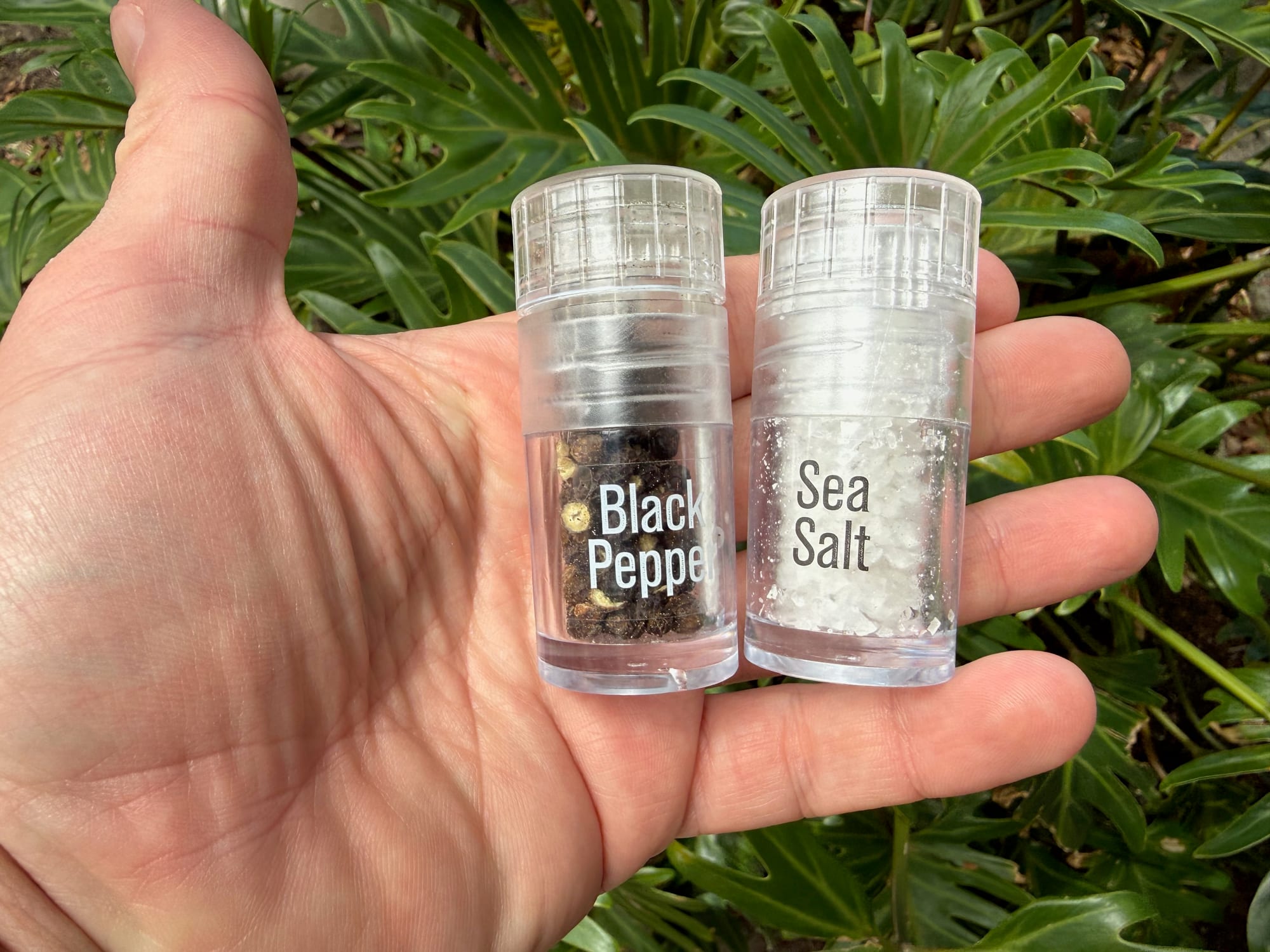 The AGS mini black pepper and sea salt grinders held in the palm of a hand