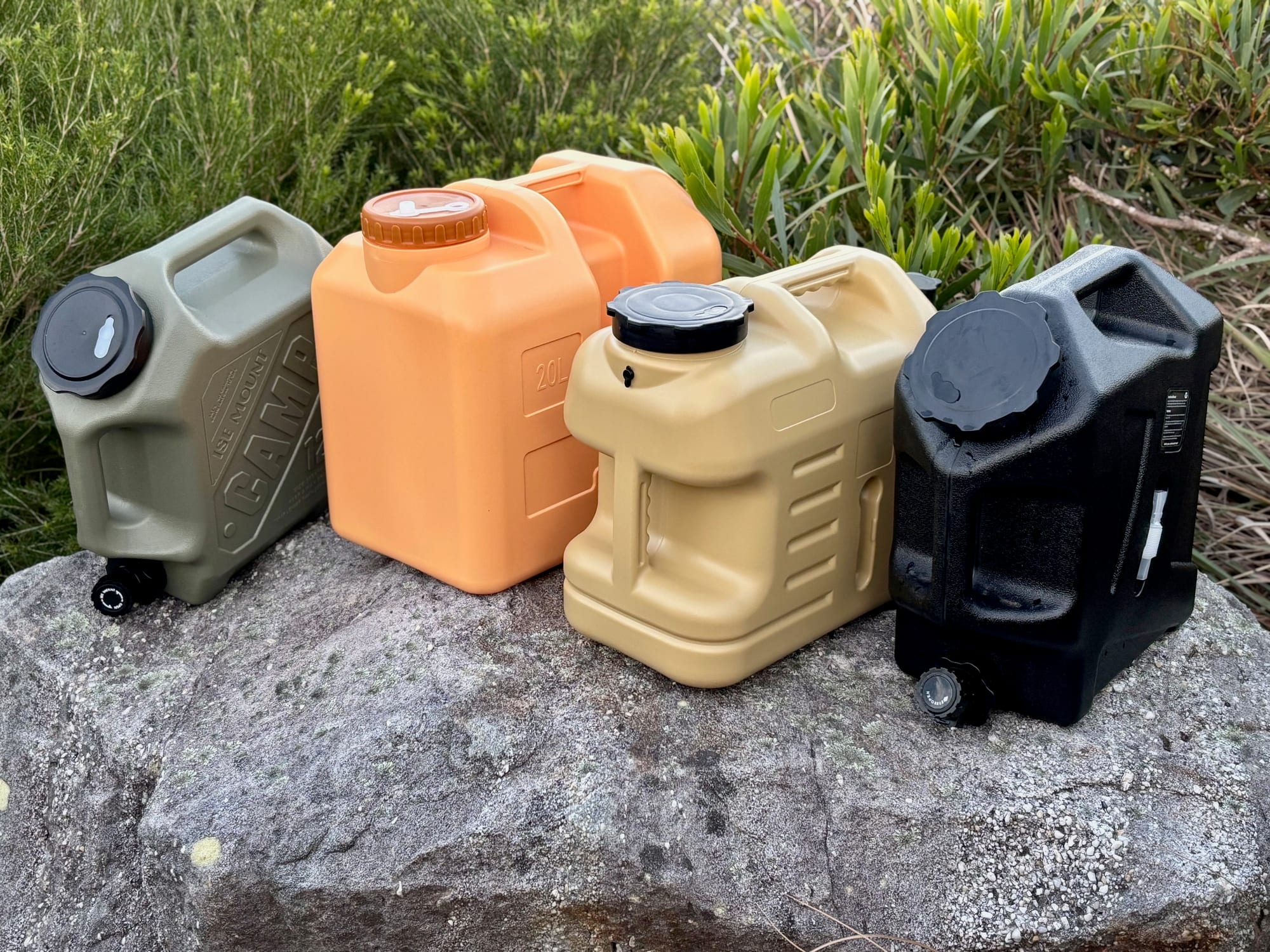 The beige 18.5 L container on a rock with a green 12 L, an orange 20 L and a black 12 L container
