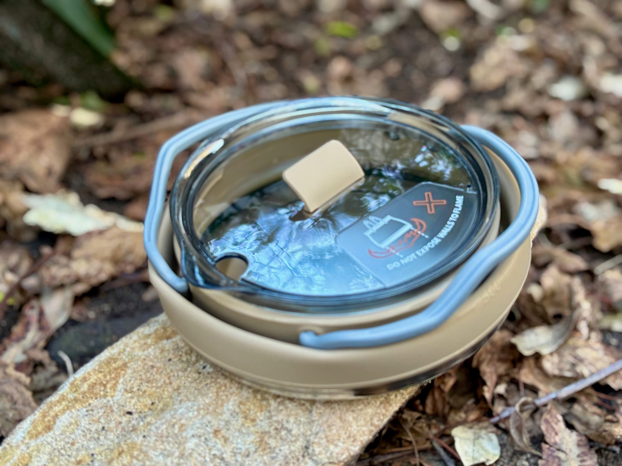 The Aimall kettle collapsed flat, with its clear lid and the handle wrapped around it