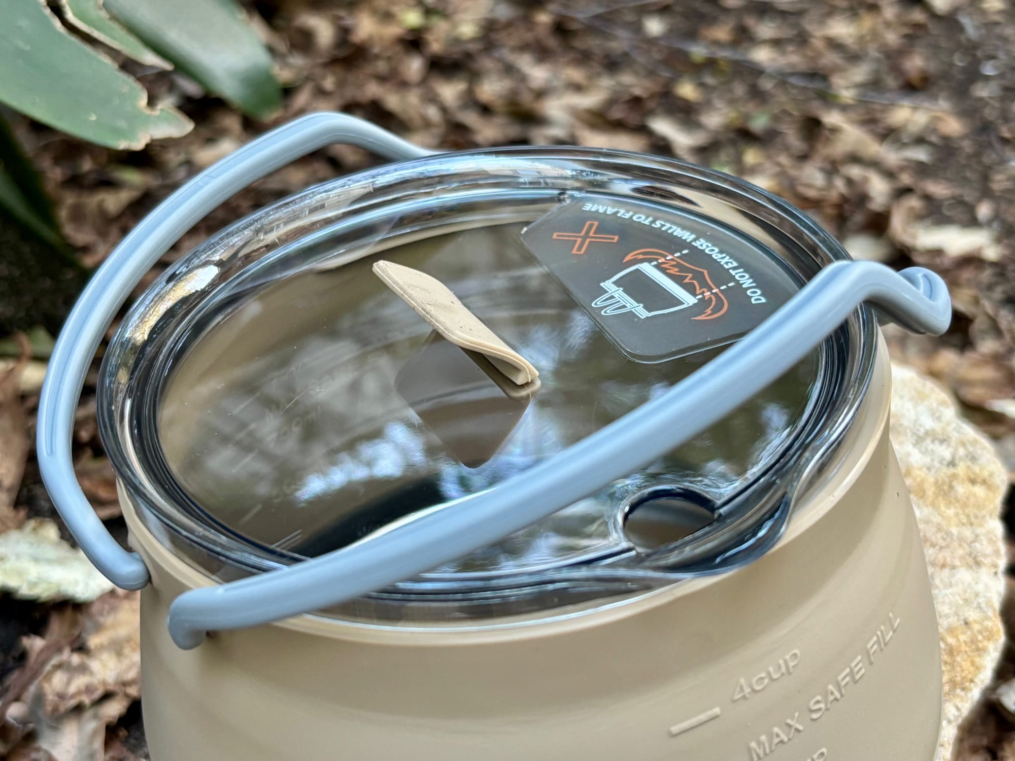 The clear lid of the Aimall kettle with its warning label not to expose the walls to flame