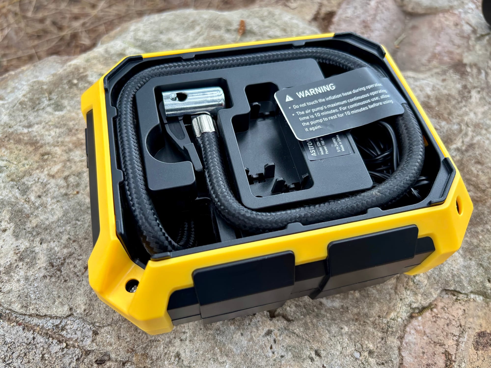 The braided hose and clamp connector stored in the compartment at the back of the AstroAI inflator
