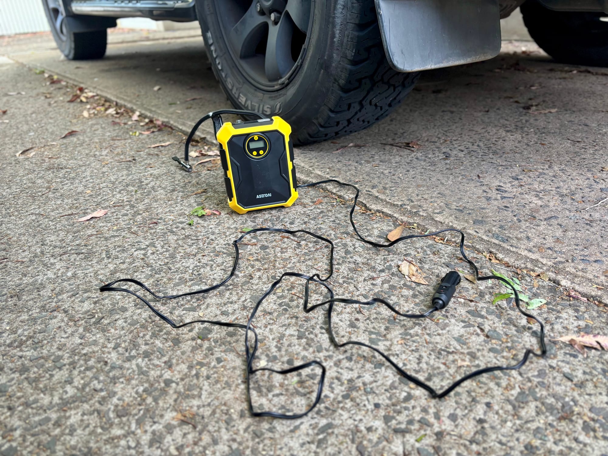 The AstroAI tyre inflator with its 3 m power cord and 12V plug laid out