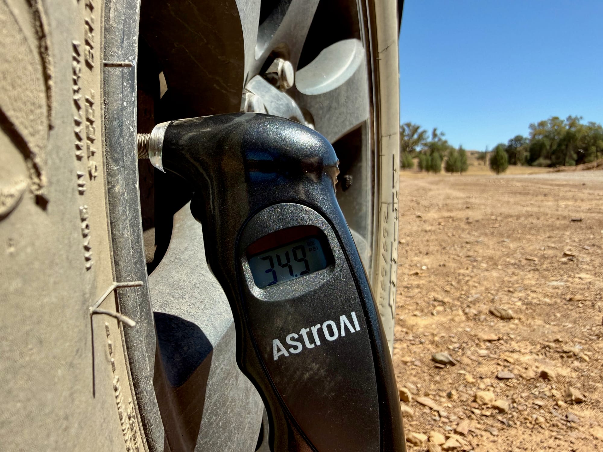 The AstroAI gauge on a dusty wheel in the outback, reading 34.9 PSI
