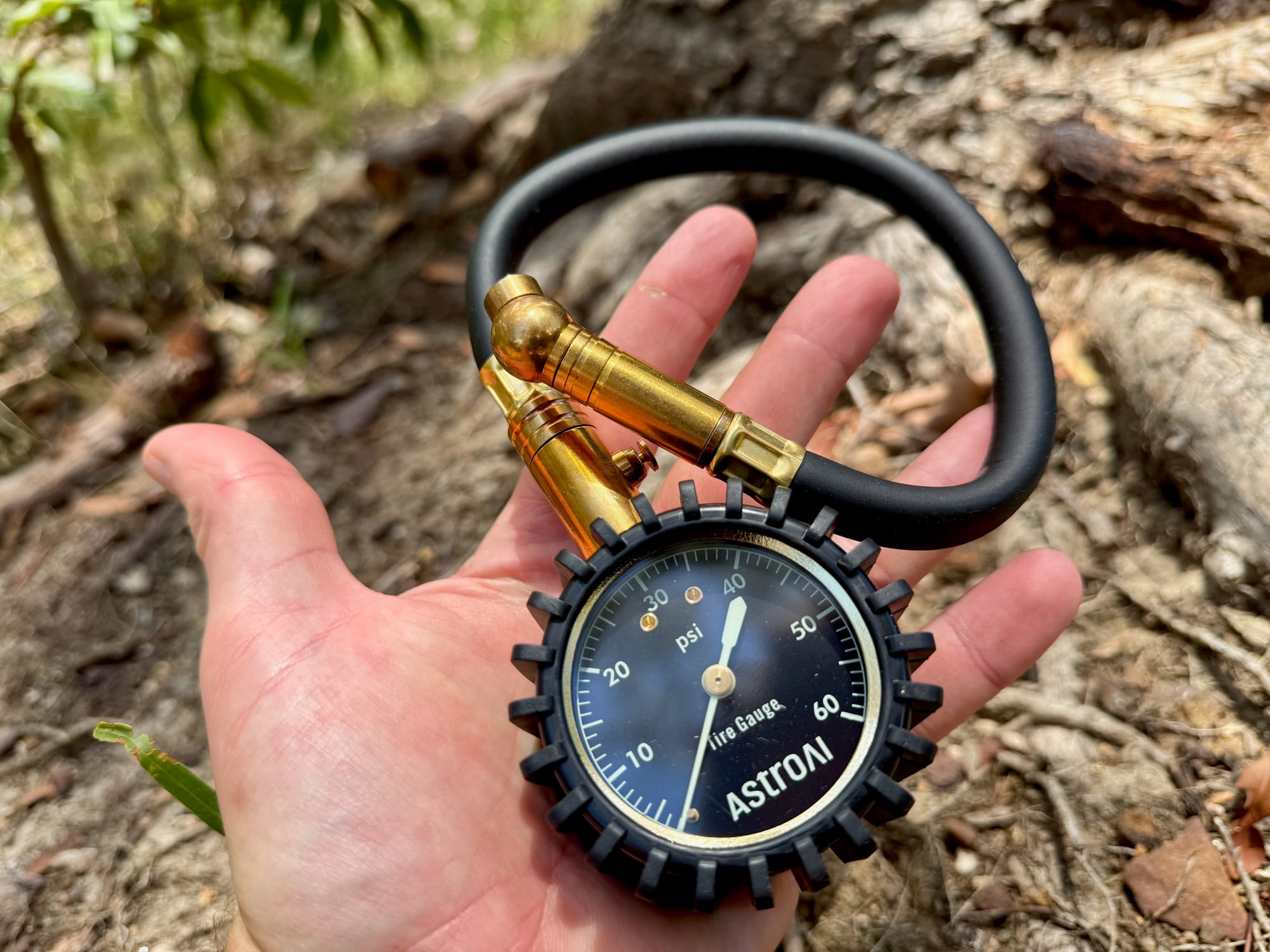 The AstroAI mechanical tyre pressure gauge lying in an open hand