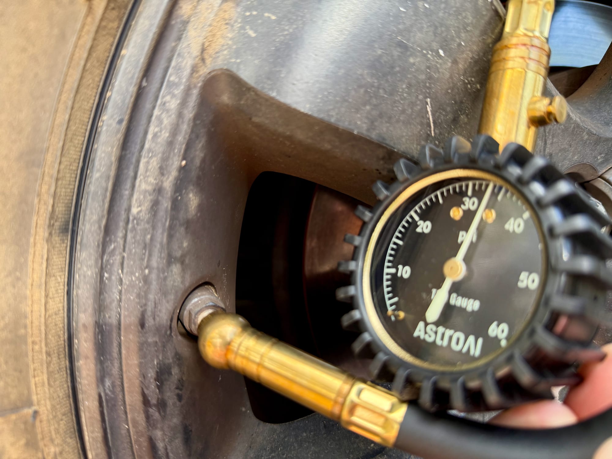 The brass swivel chuck of the AstroAI gauge on a tyre valve, with the dial beside it