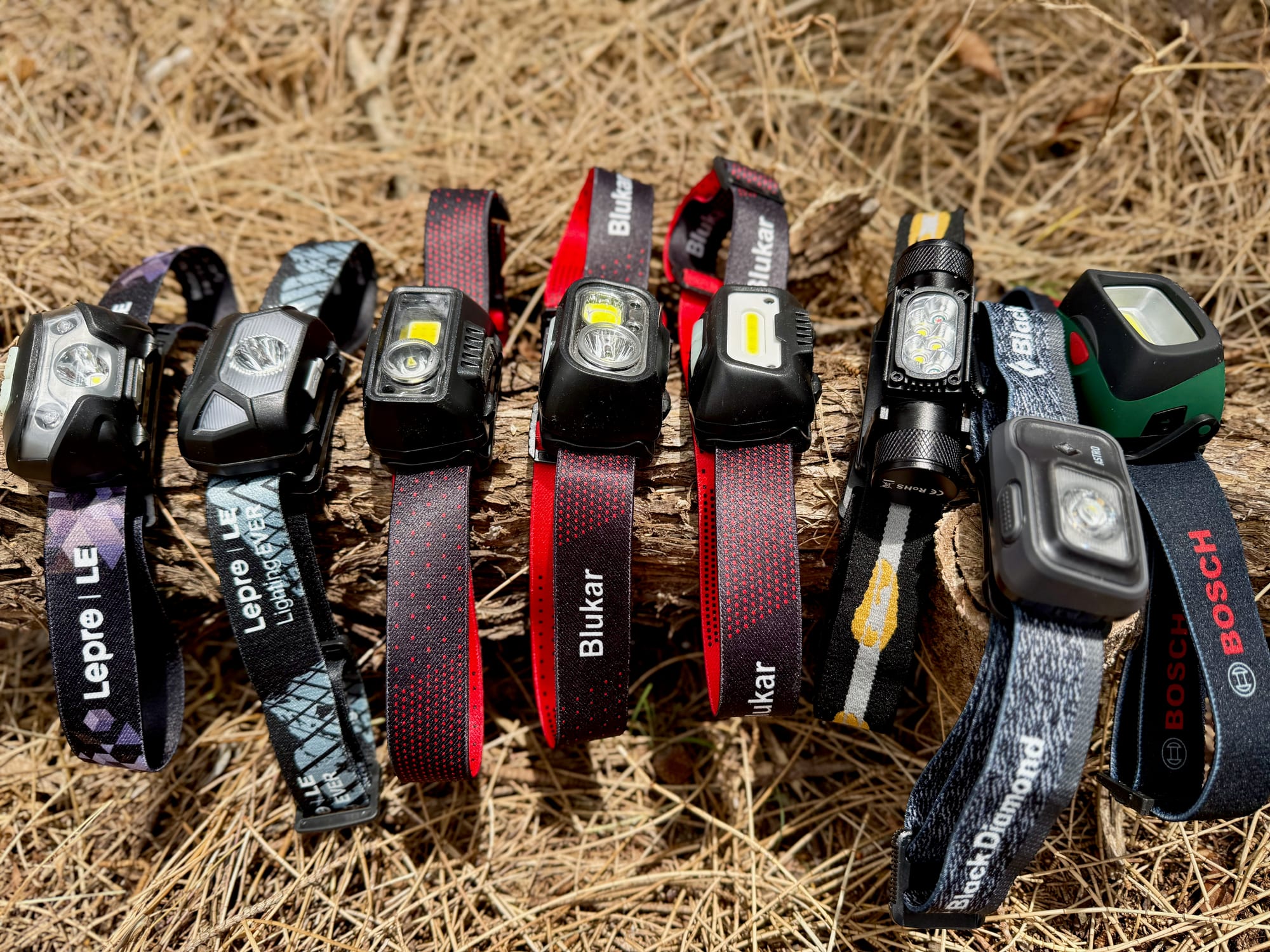 Camping head torches lined up on a log