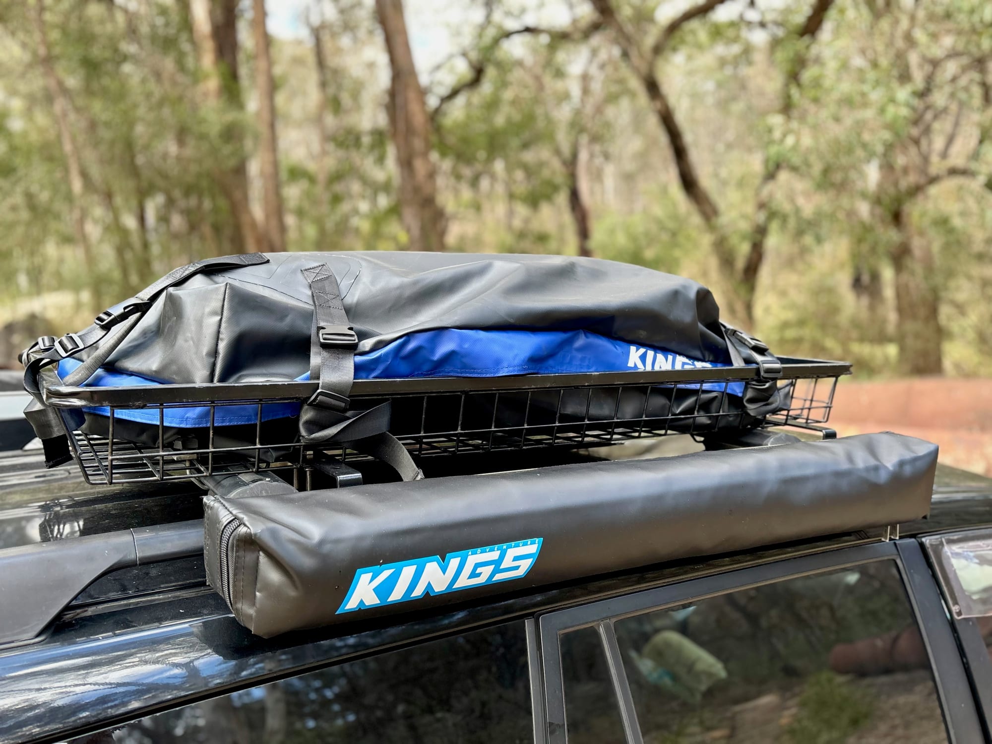 A Kings Roof Top Bag strapped into the roof basket of our 4WD at a bush camp, above the rolled-up Kings awning