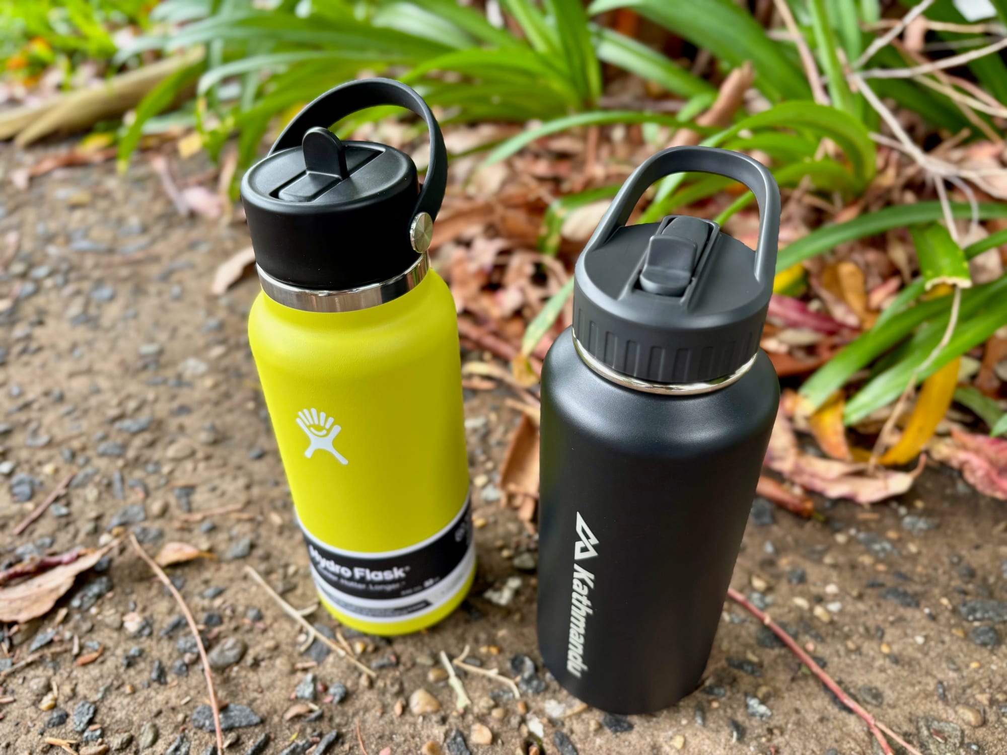 A Hydro Flask and a Kathmandu insulated water bottle side by side, both with their straws flipped up
