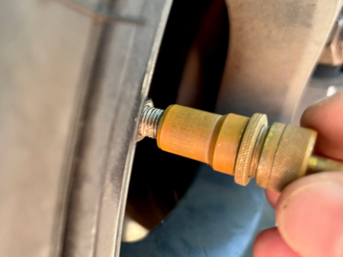 A brass automatic tyre deflator being screwed onto the valve of a 4WD tyre