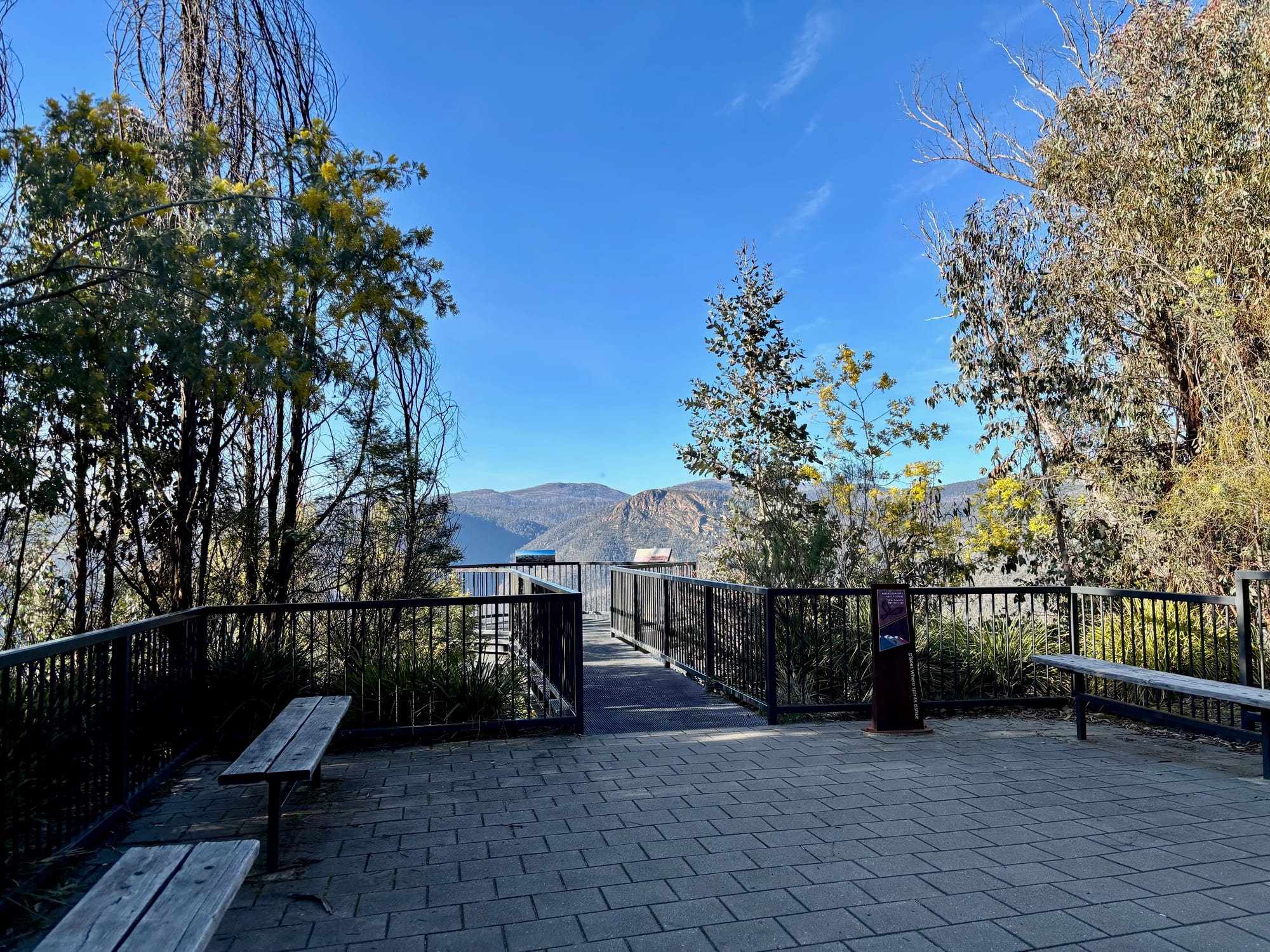 Bench seats and the metal walkway with handrails out to the fenced platform at Black Perry Lookout