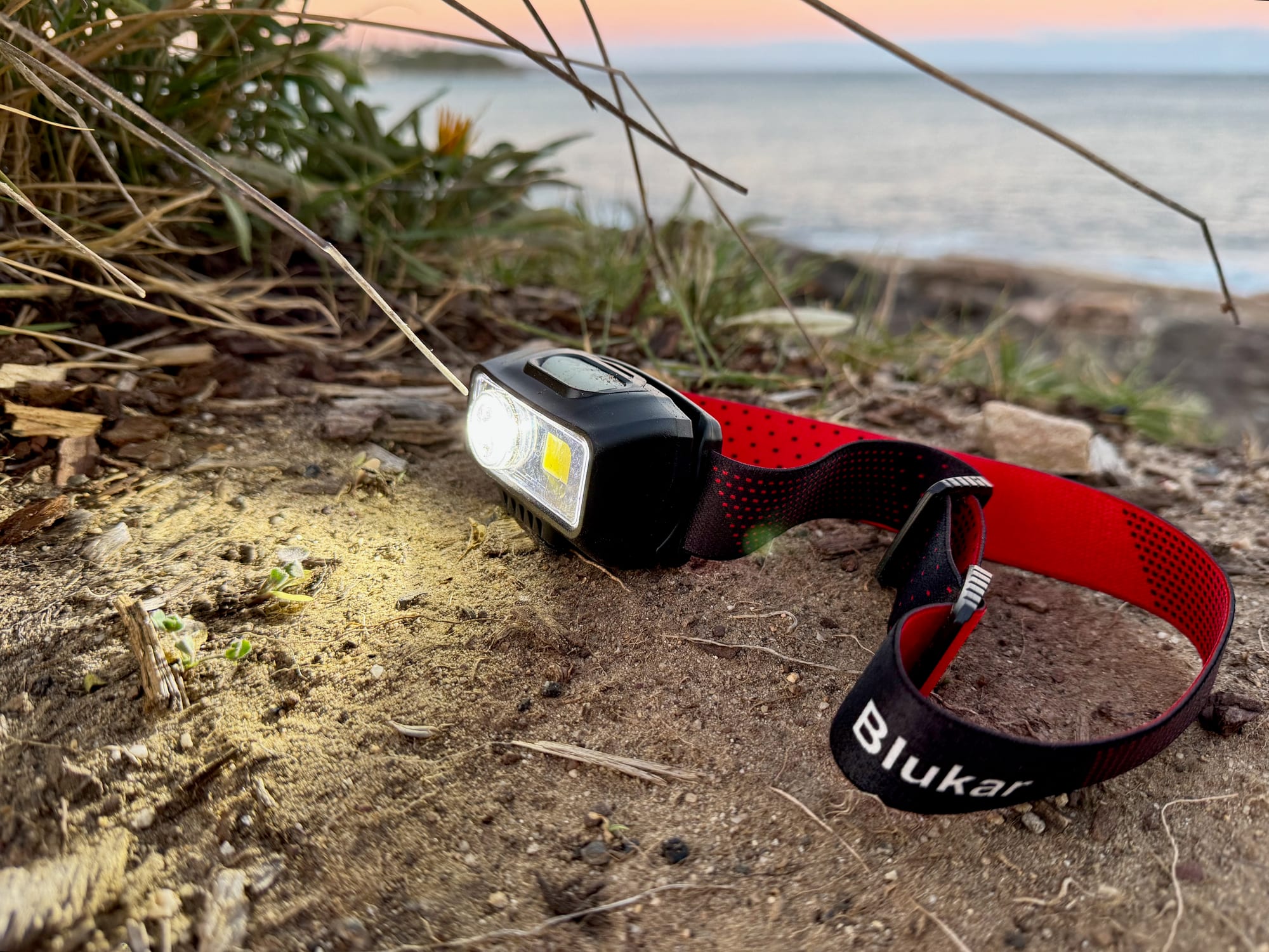 The Blukar K9111 headlamp switched on at dusk, by the sea