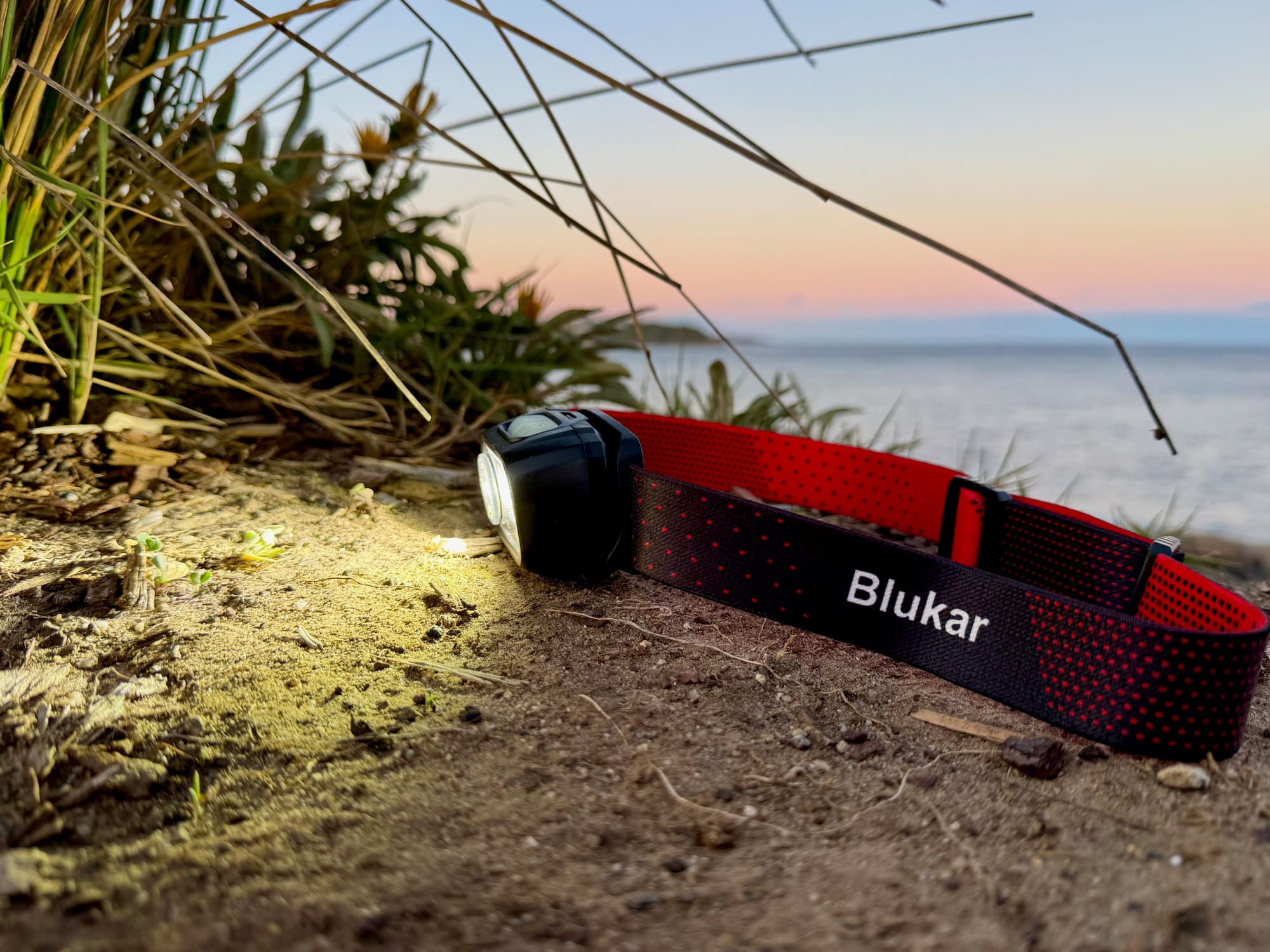 The Blukar K9125 headlamp switched on at dusk, by the sea