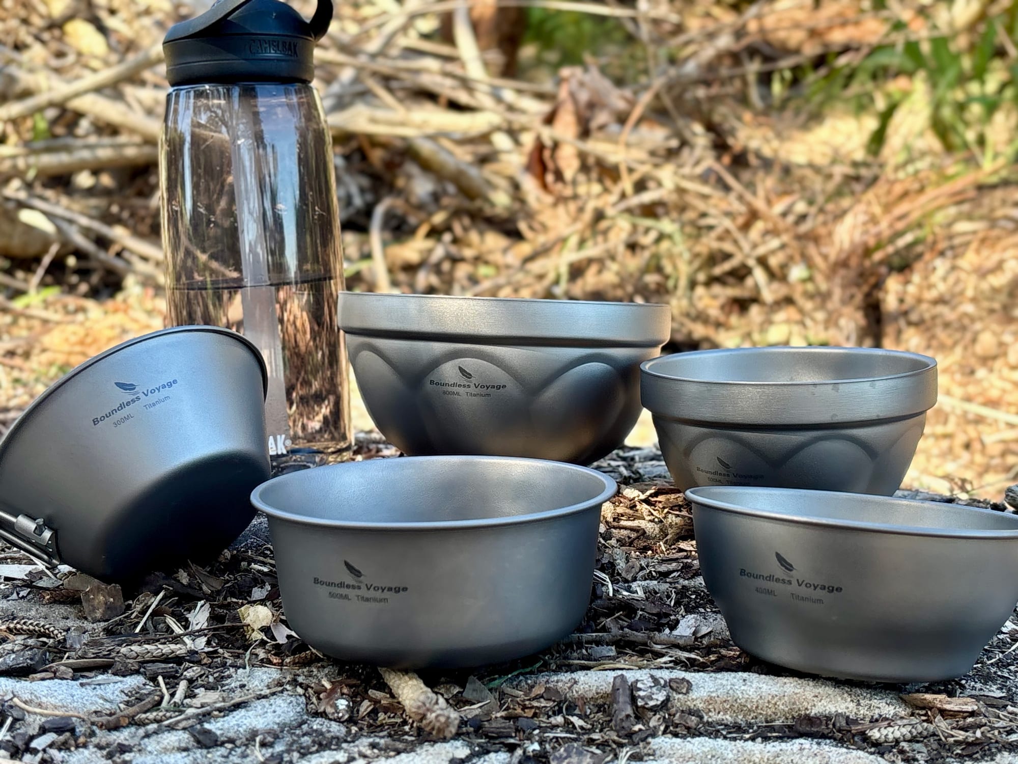 The 300 ml bowl with its handle, next to other Boundless Voyage titanium bowls and a drink bottle
