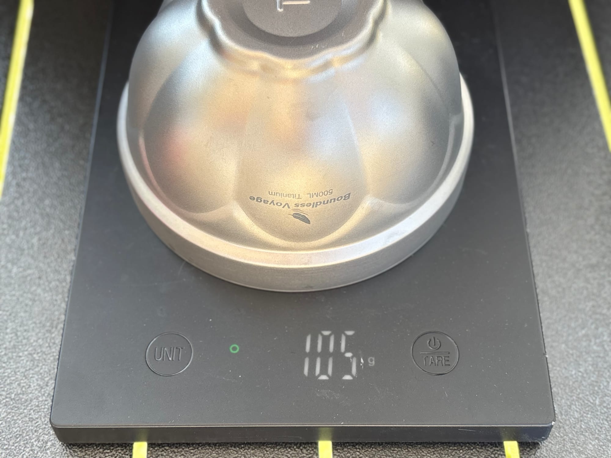 The empty titanium bowl upside down on a kitchen scale showing 105 g
