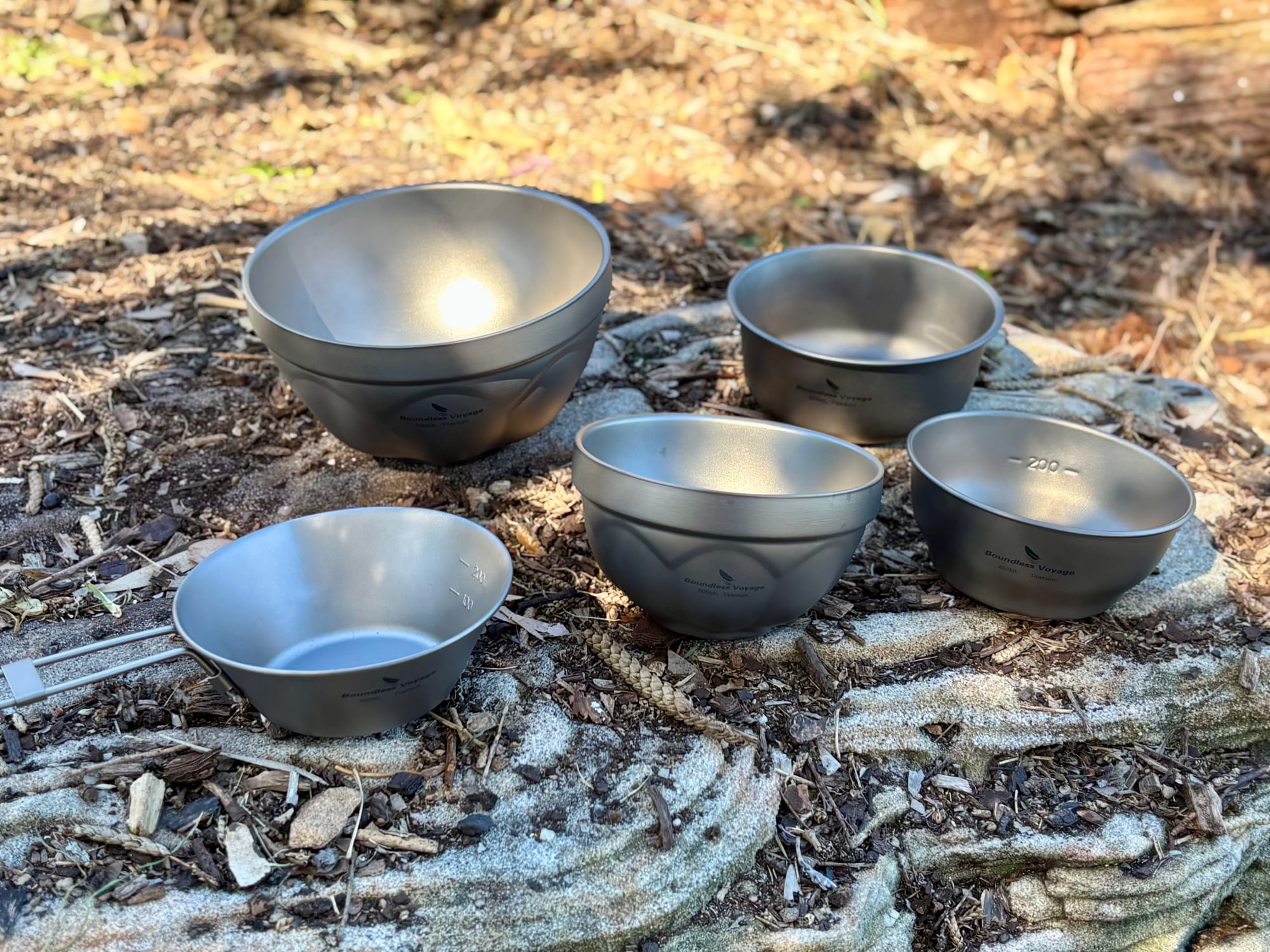 Five Boundless Voyage titanium bowls on a rock, including the double-walled 500 ml and 800 ml and the single-walled bowls
