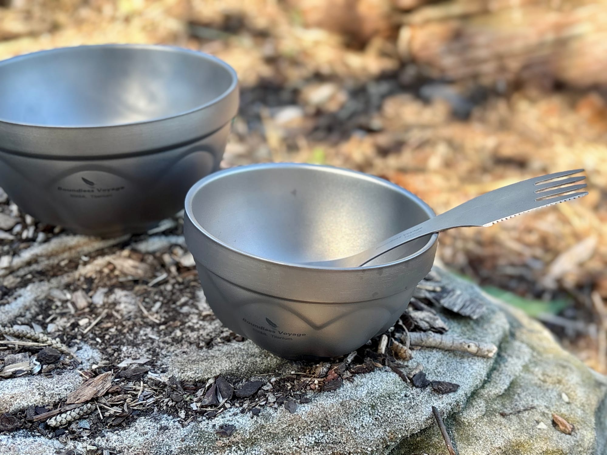 The 500 ml titanium bowl with a titanium spork, on a rock in the bush with the 800 ml bowl behind