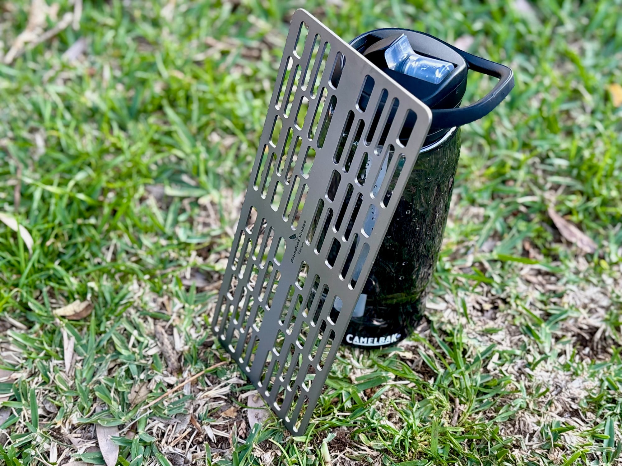 The Ti2023C titanium grill plate standing next to a 1 litre water bottle on the grass