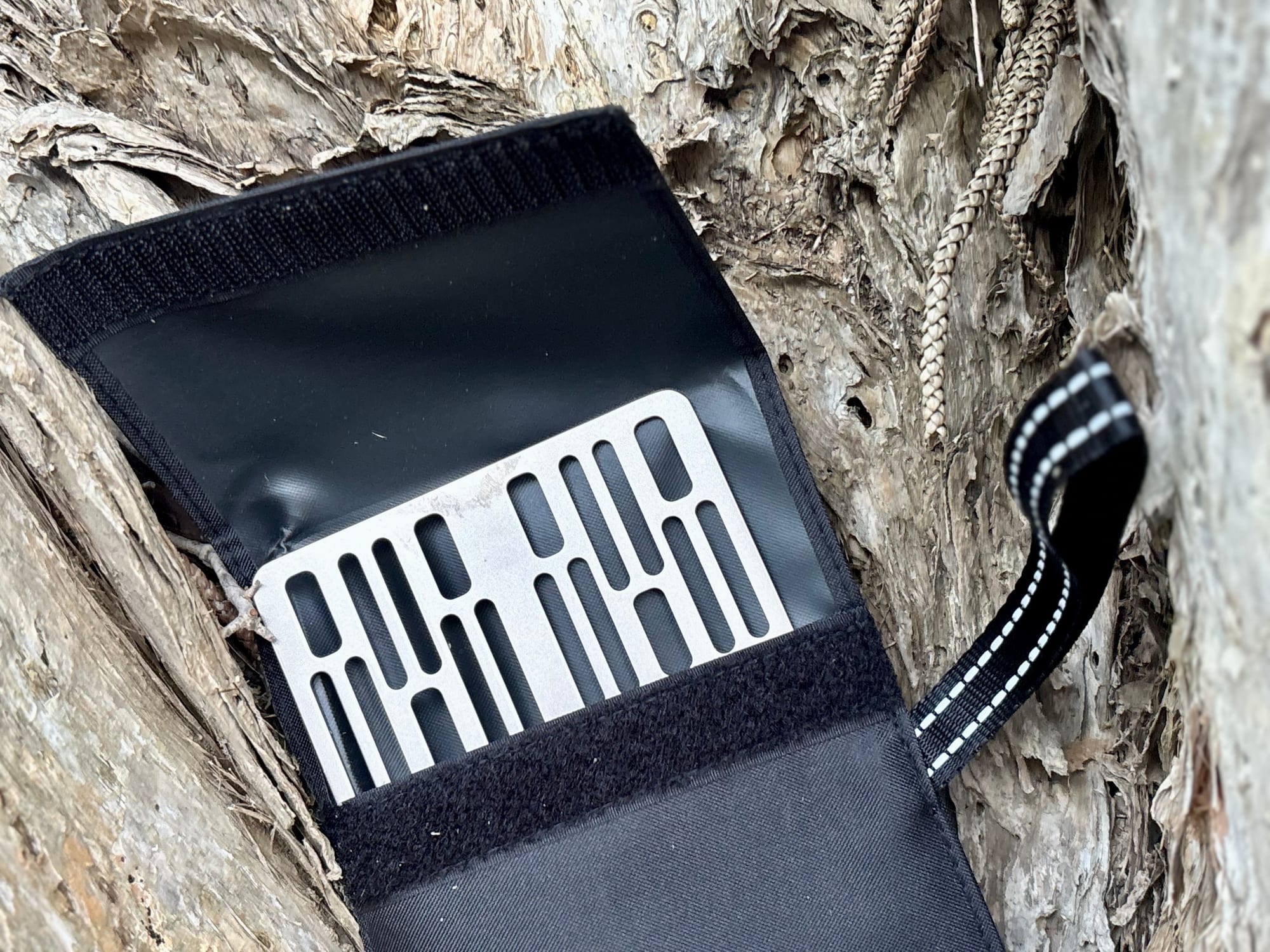The Ti2023C titanium grill plate half out of its open sleeve, showing the velcro flap