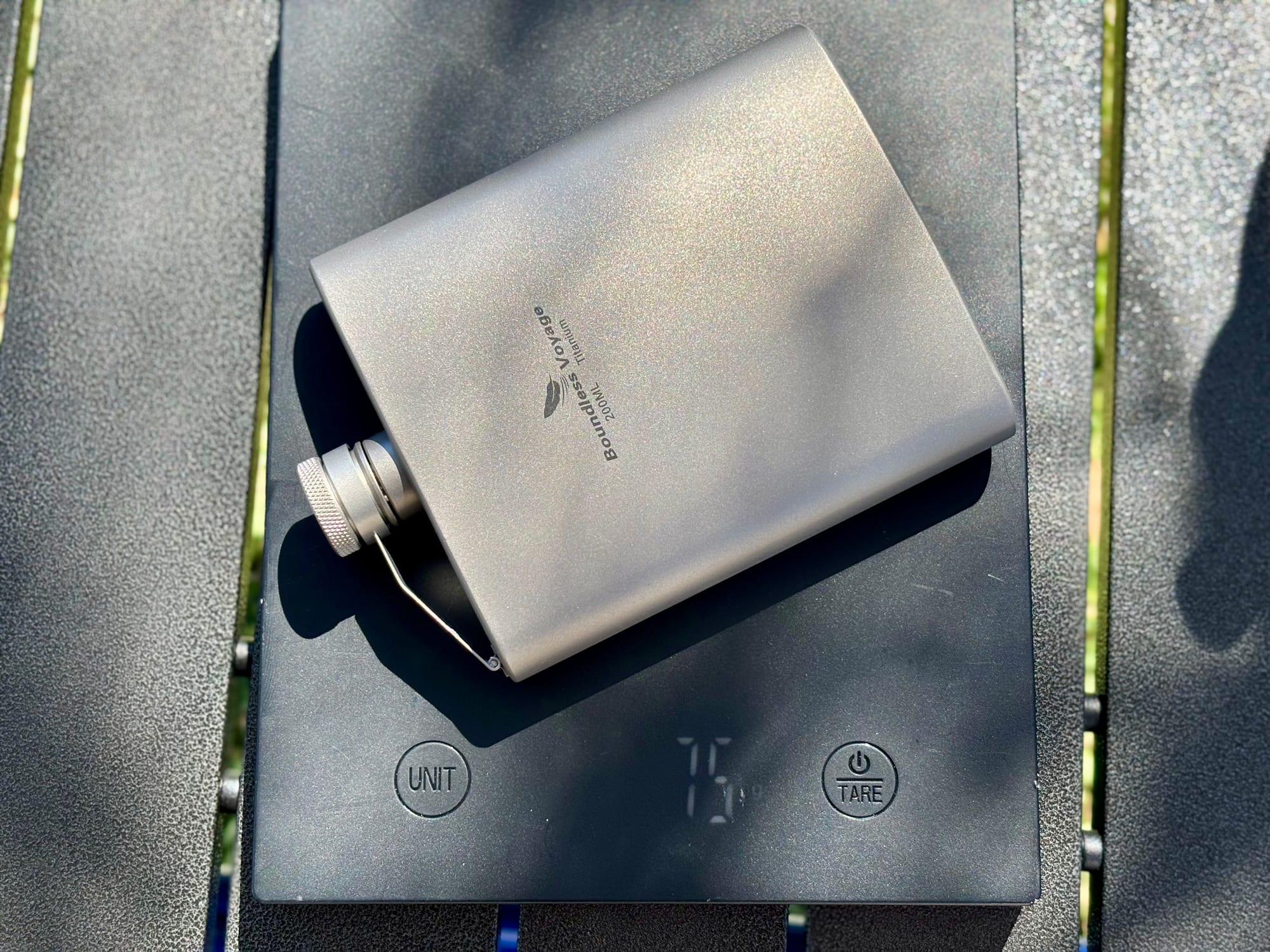 The Boundless Voyage hip flask lying on a kitchen scale showing 75 g