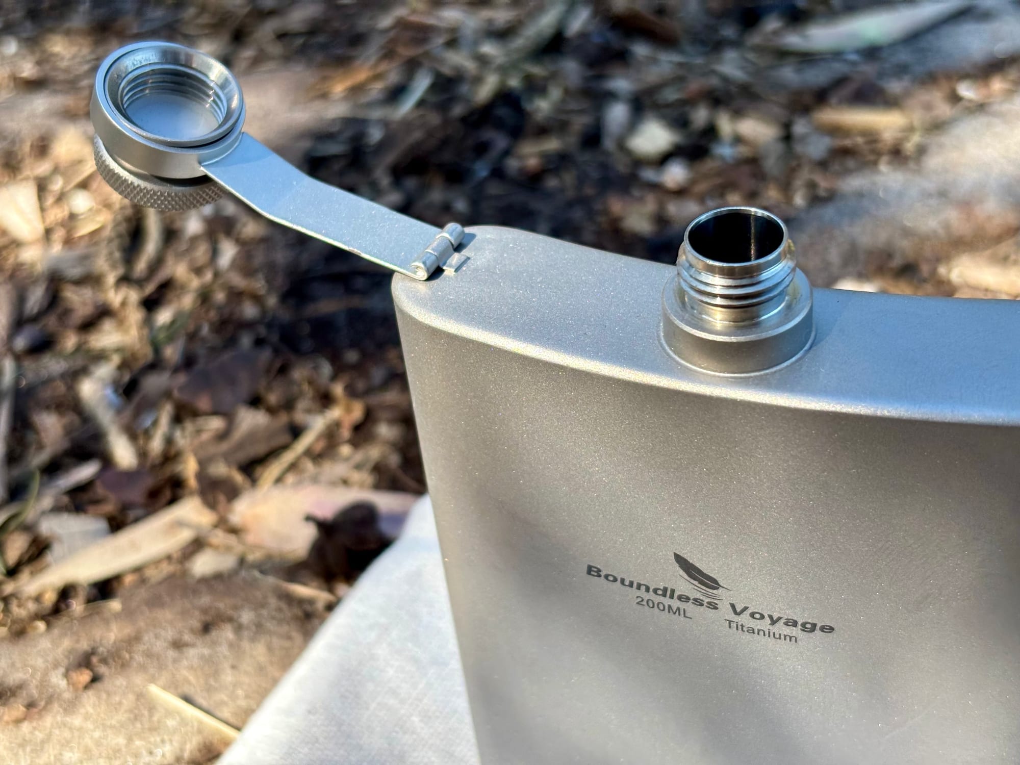 The flask with its cap swung open on the arm, showing the threaded neck