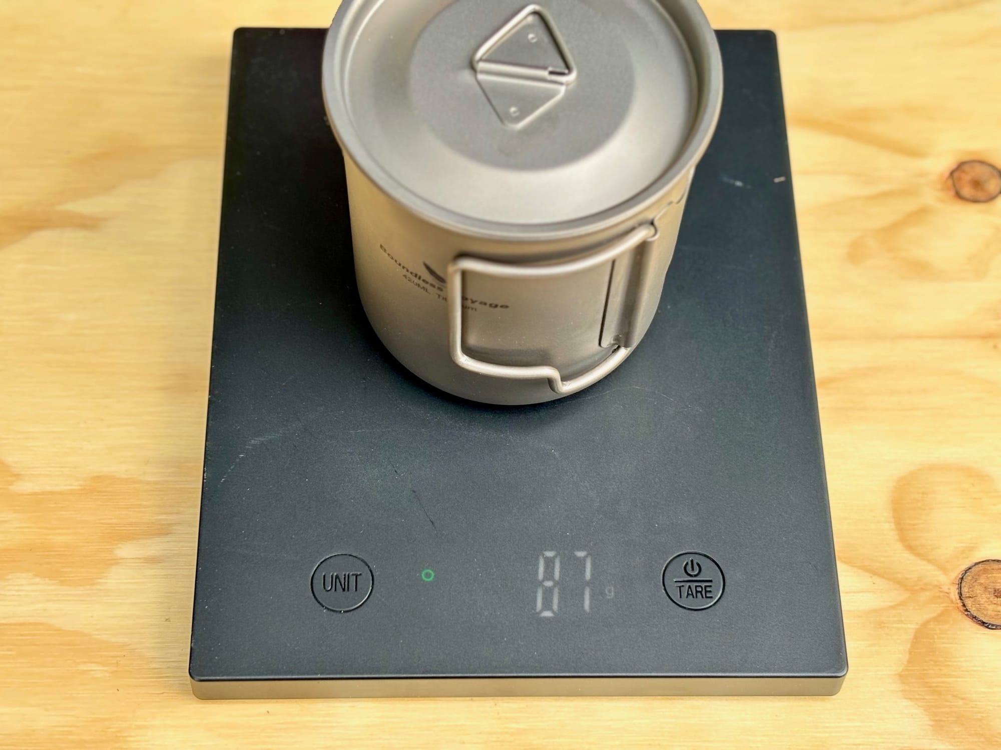 The titanium mug with its lid on a kitchen scale showing 87 g