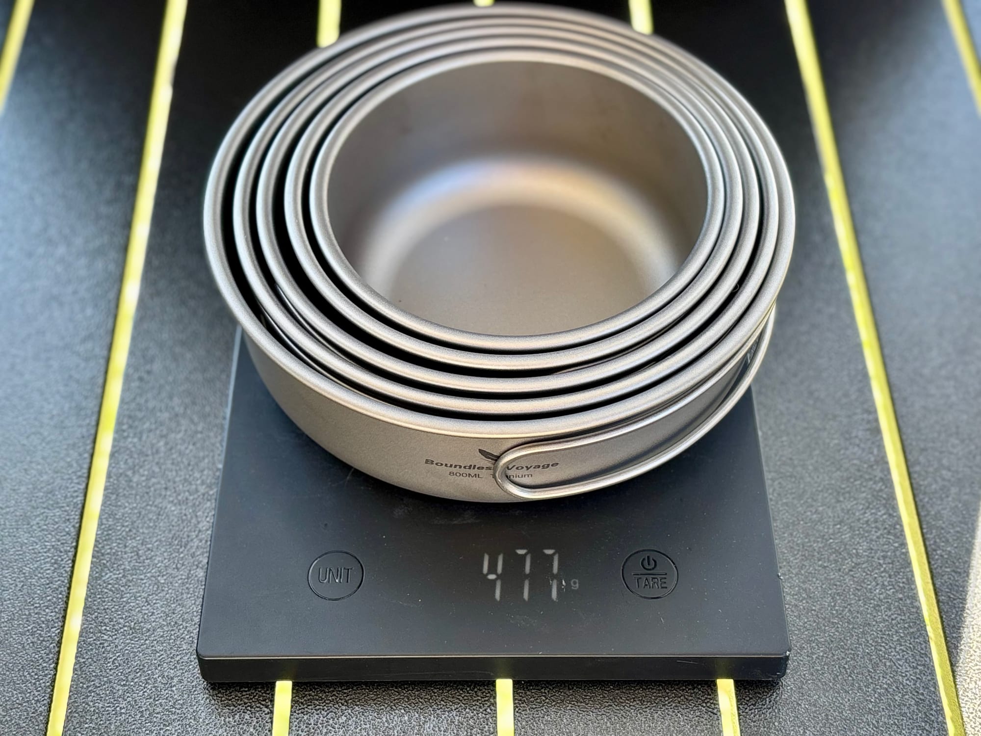 The five nested titanium pans on a digital scale showing 477 grams