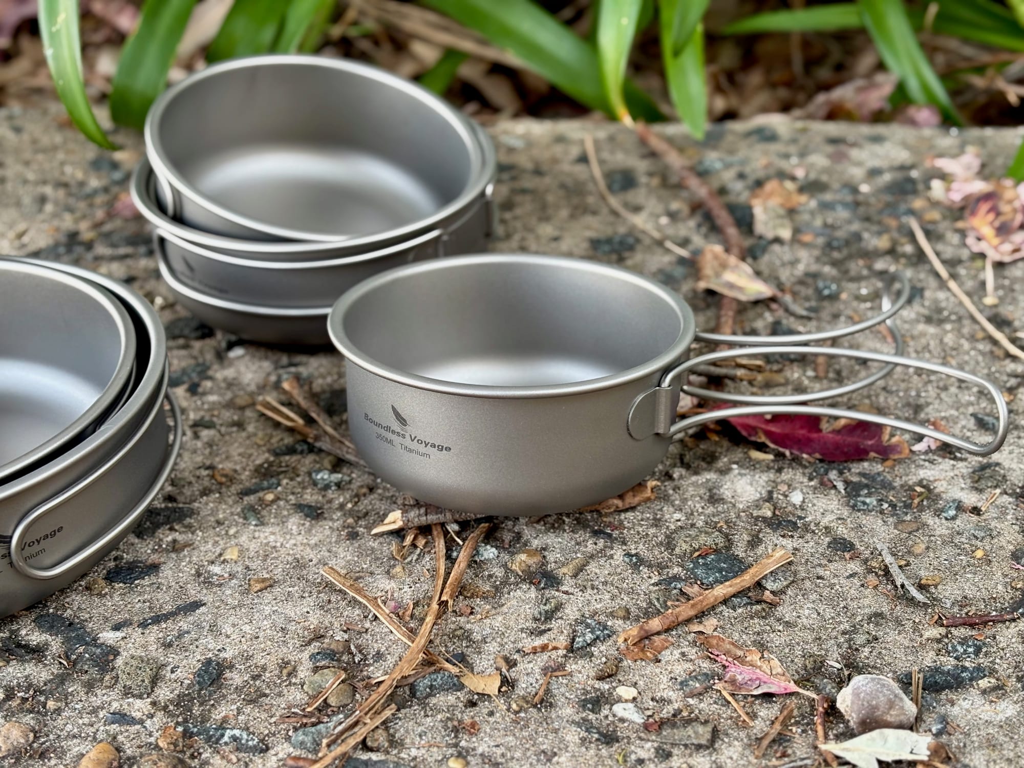 One Boundless Voyage titanium pan with its handle folded out, next to the other four stacked