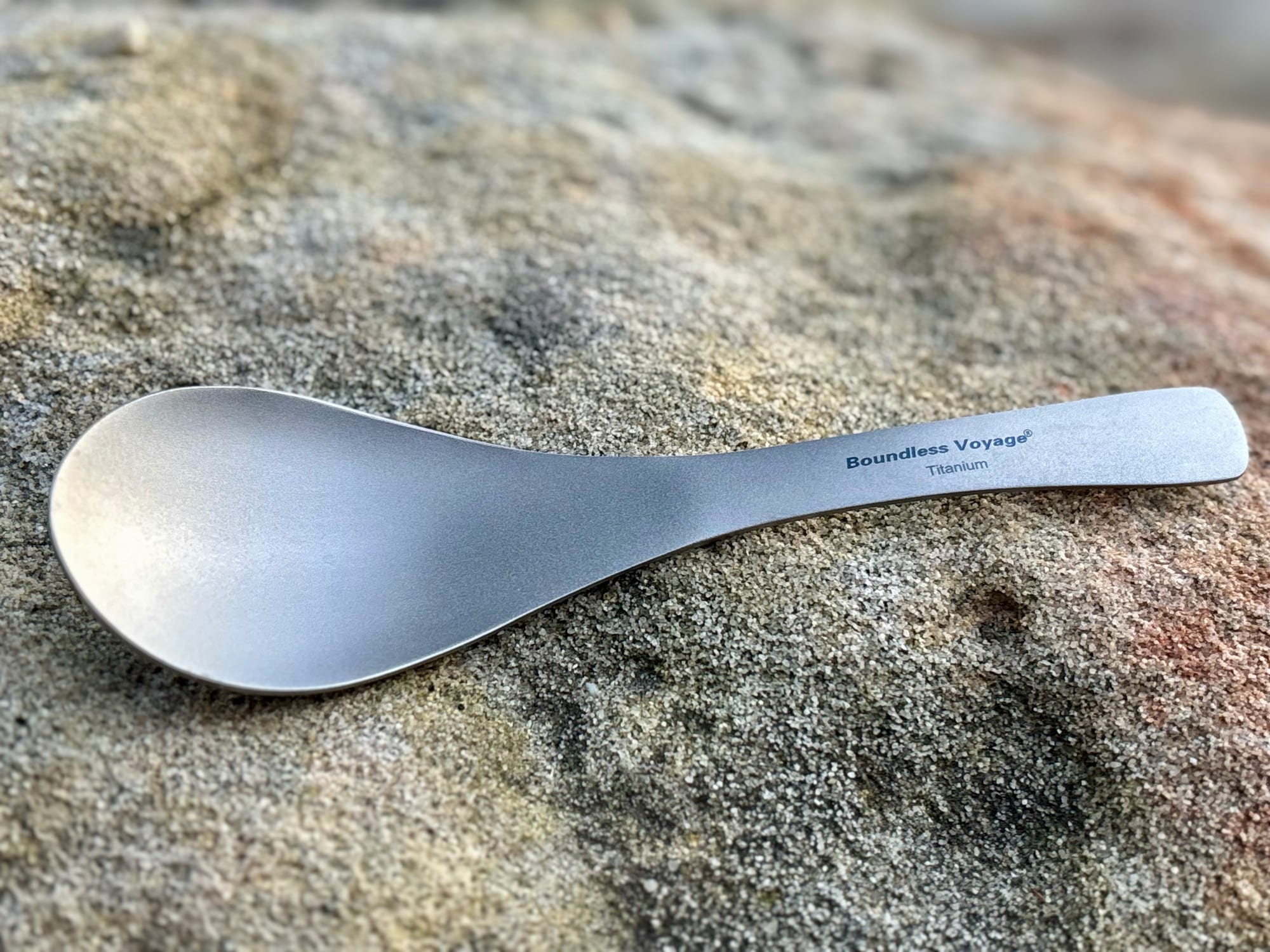 The full length of the Boundless Voyage titanium spoon on a sandstone rock