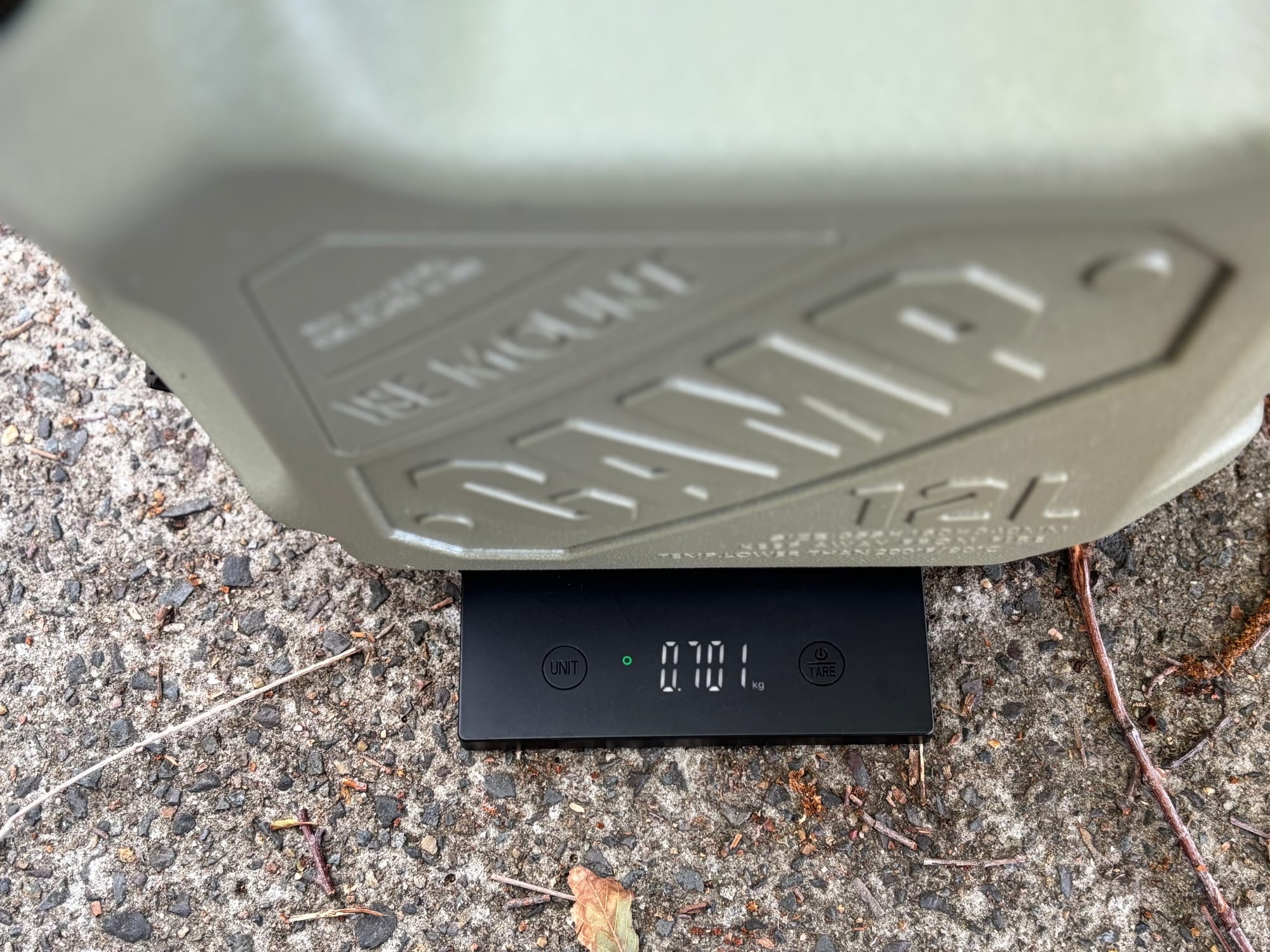 The green 12 L container on a kitchen scale showing 0.701 kg