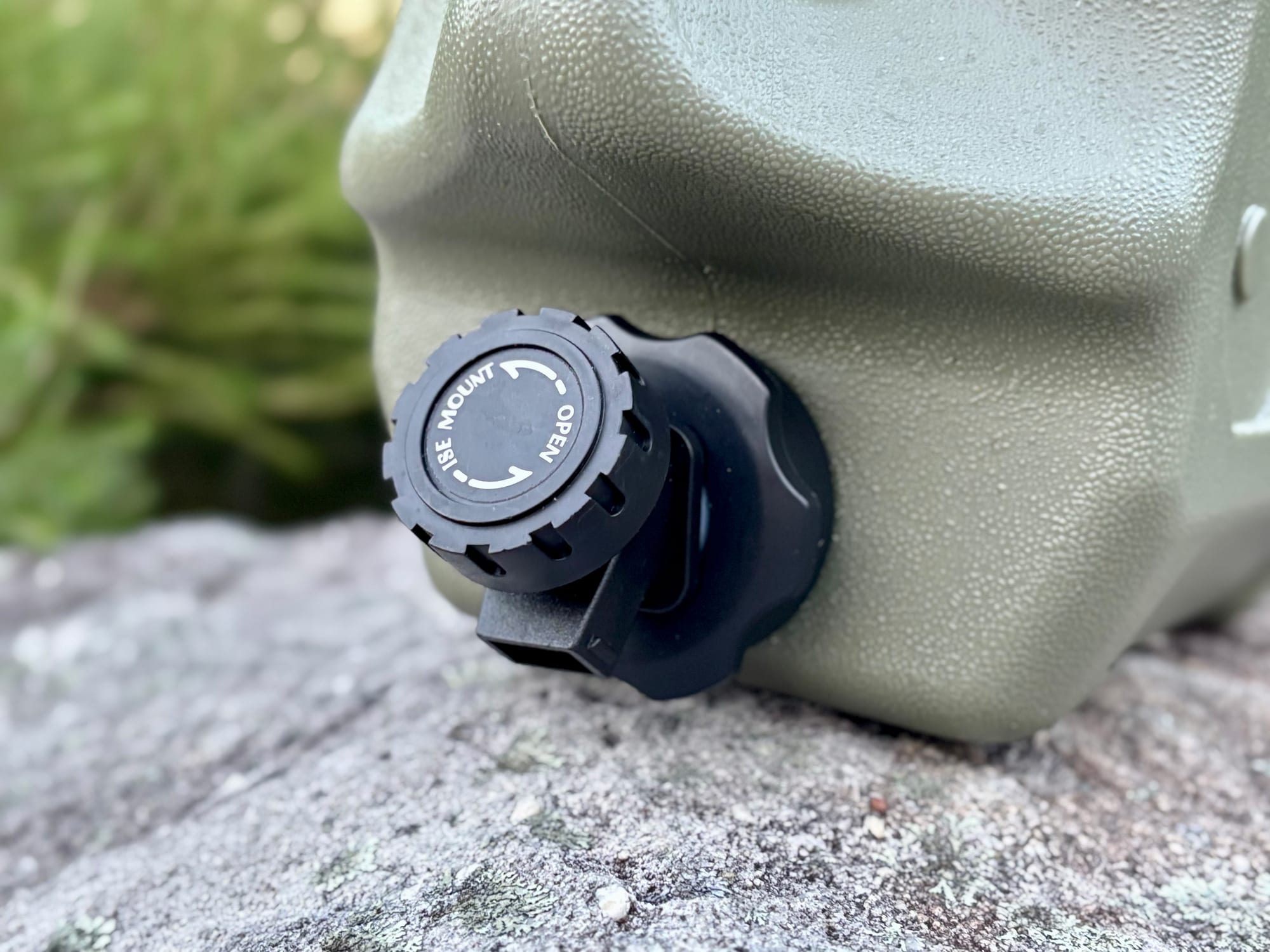 The black tap at the bottom of the green container, on a rock
