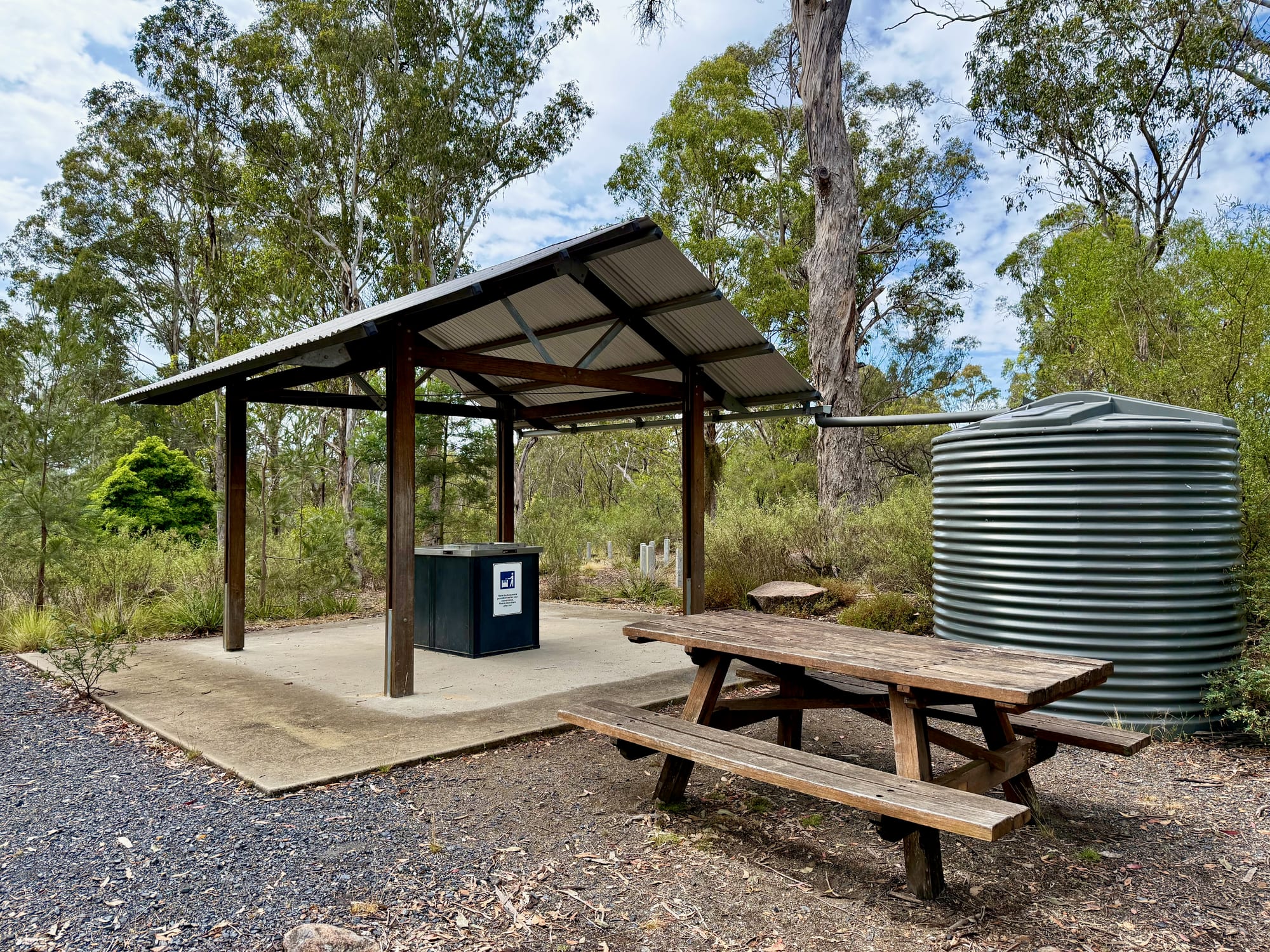 A barbecue shelter with a picnic table and a rainwater tank at Bungonia Campground