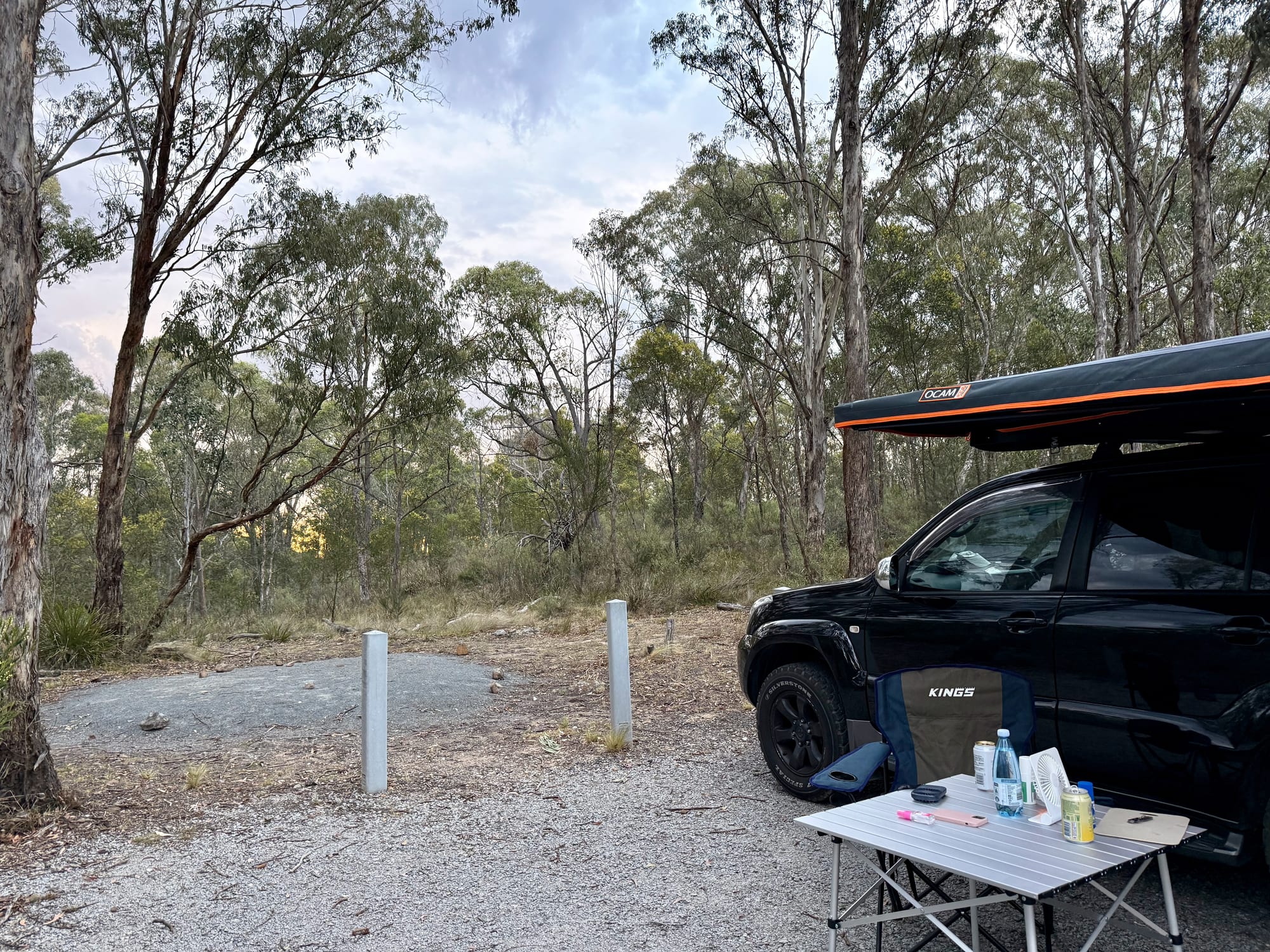 Our 4WD with the awning out, camp chairs and a table on a gravel site at Bungonia Campground