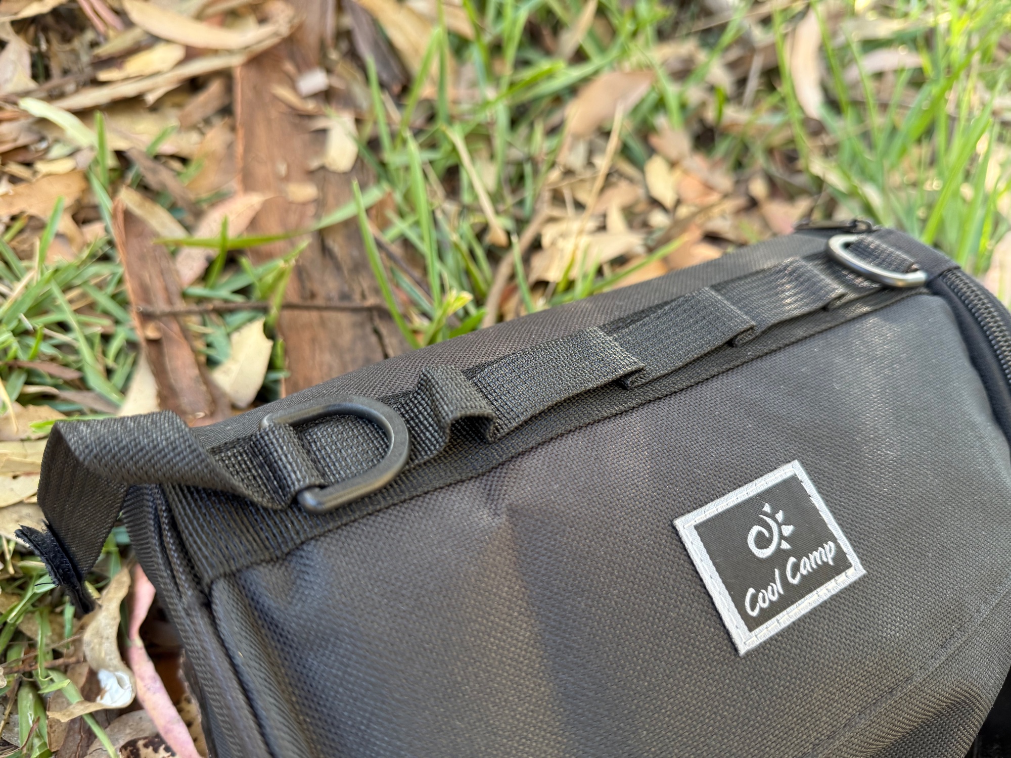 Close-up of the paper towel holder’s Cool Camp patch, webbing strap and D-ring