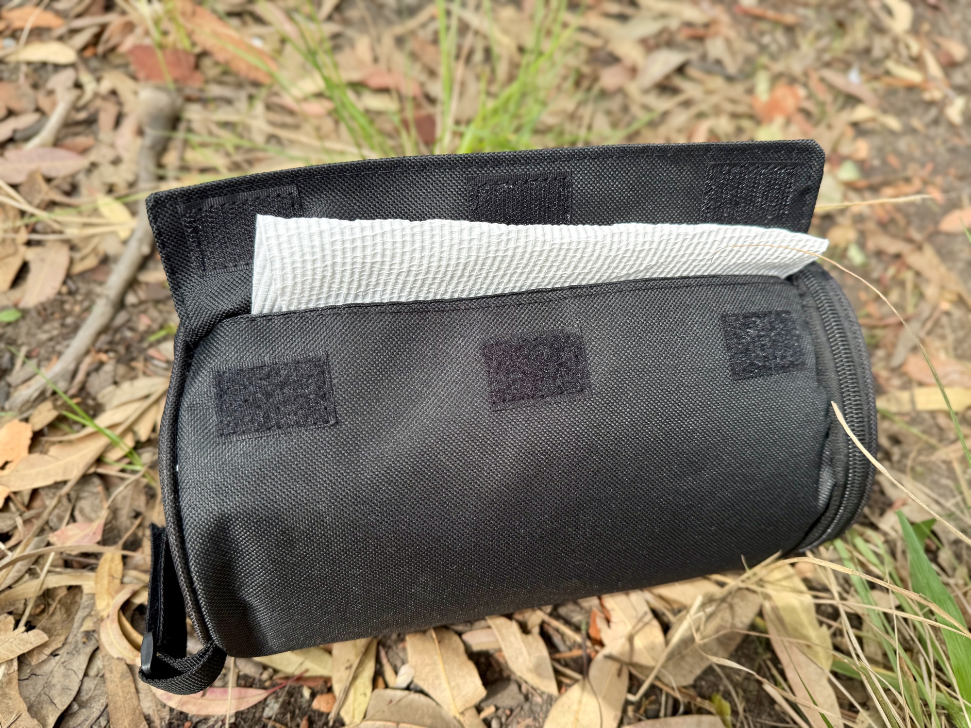 The paper towel holder with the velcro flap open and the towel showing