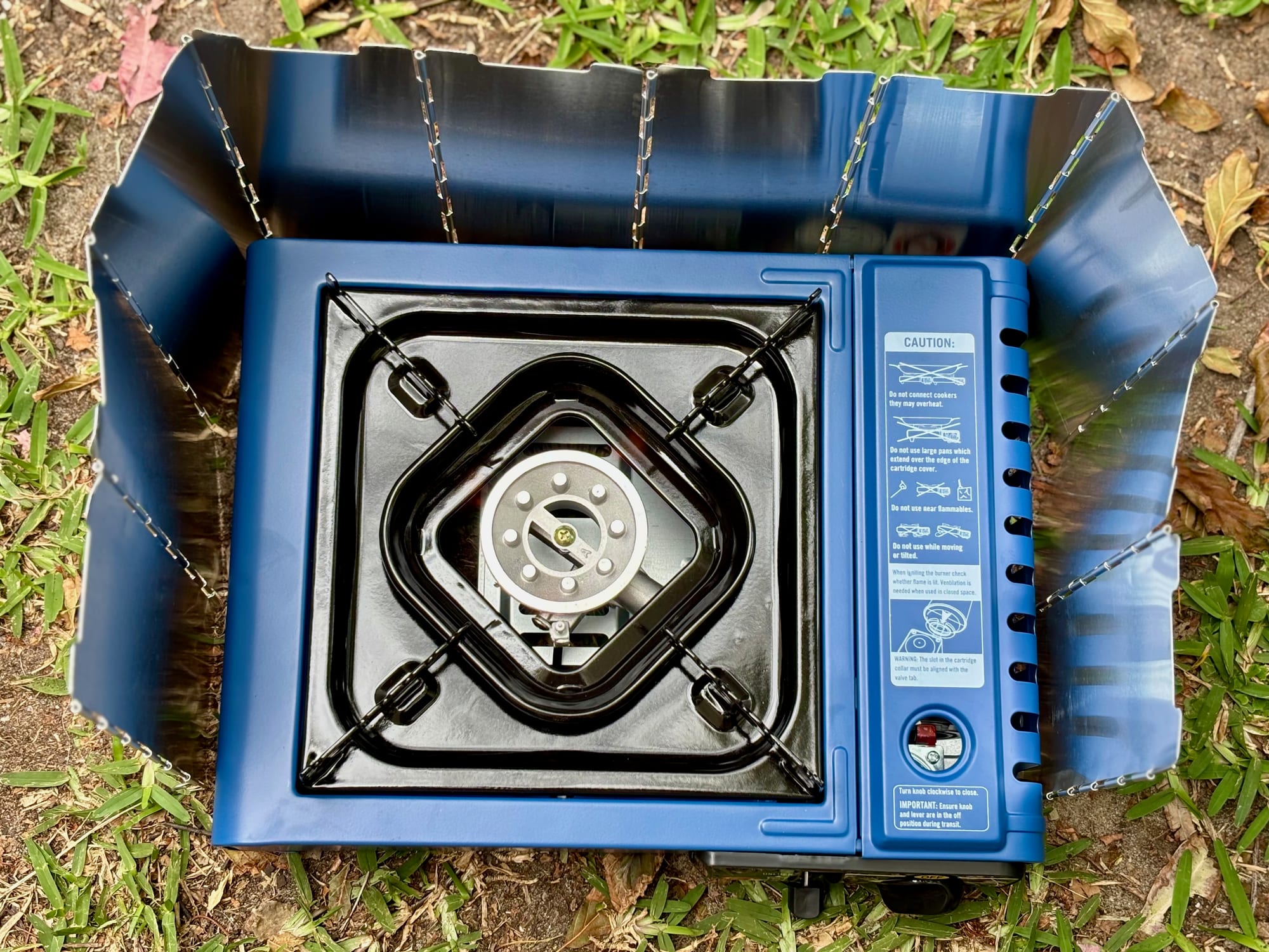 The folding windshield bent around a blue butane stove, seen from above
