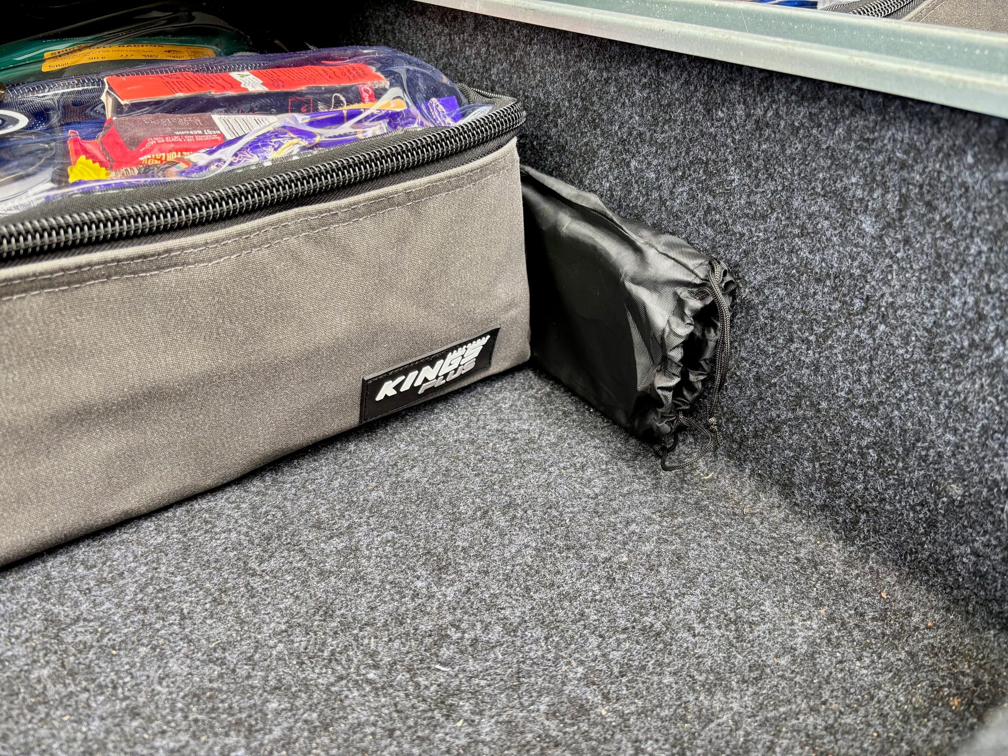 The windshield in its black drawstring bag in the back of the car, next to a storage bag