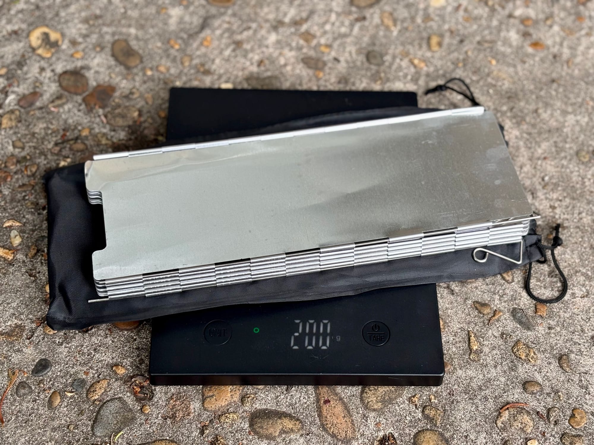 The folding windshield and its bag on a scale showing 200 g