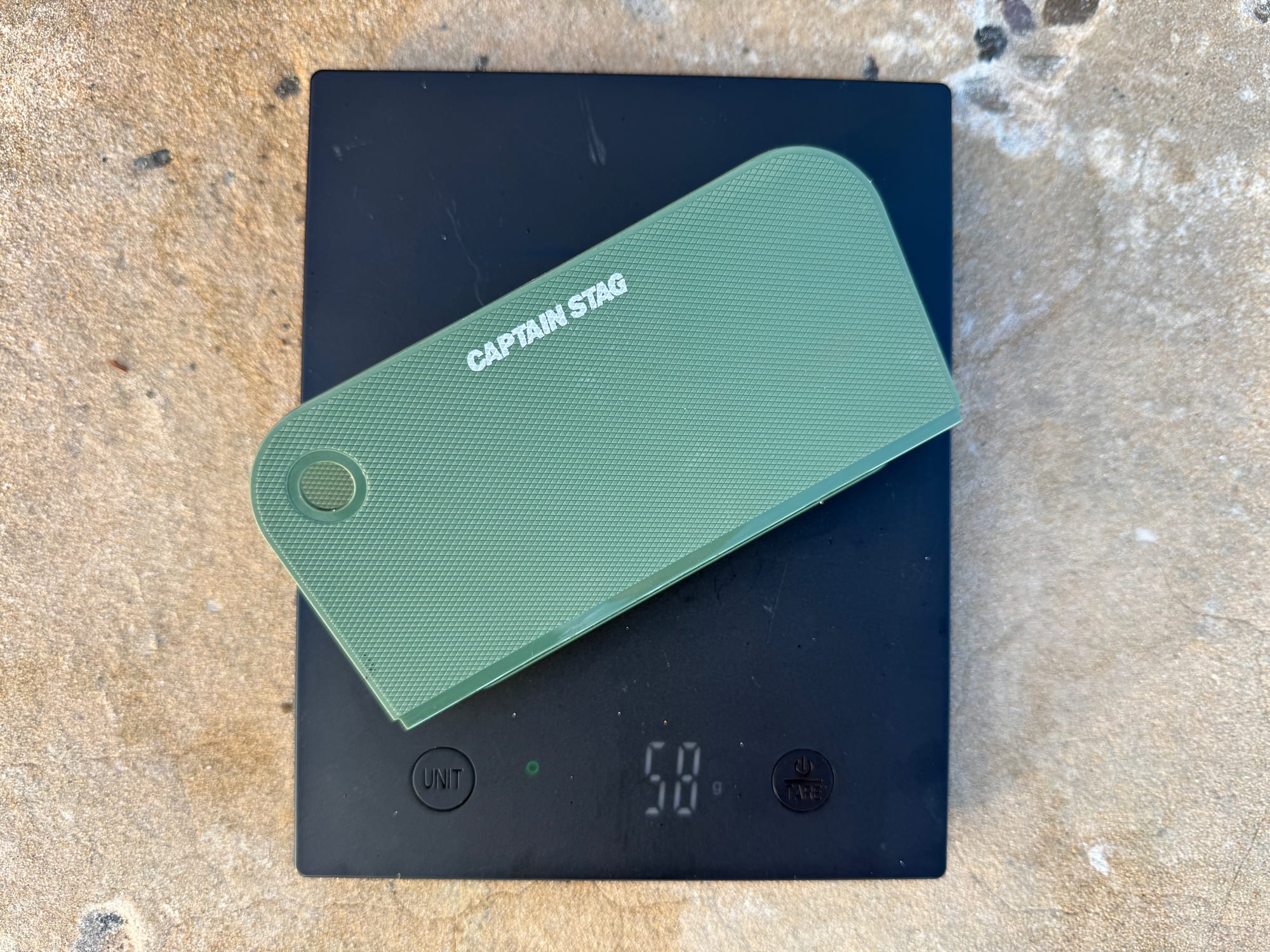 The Captain Stag cutting board on a digital scale showing 58 grams