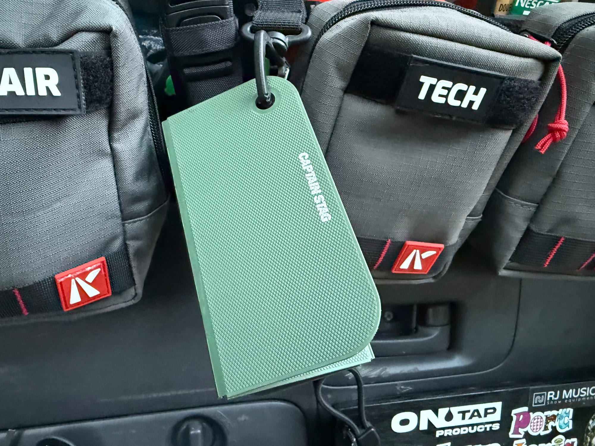 The folded Captain Stag cutting board hanging from a carabiner on the back of a car