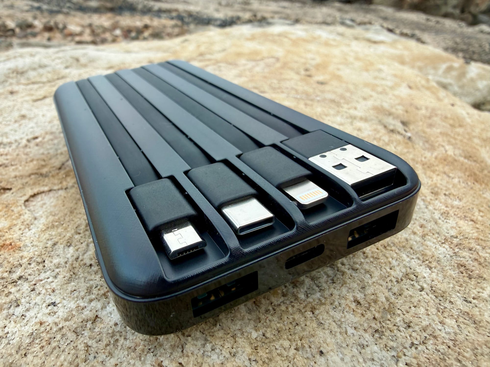 The four built-in cables of the Charmast power bank pulled out: USB-C, micro-USB, Lightning and USB-A