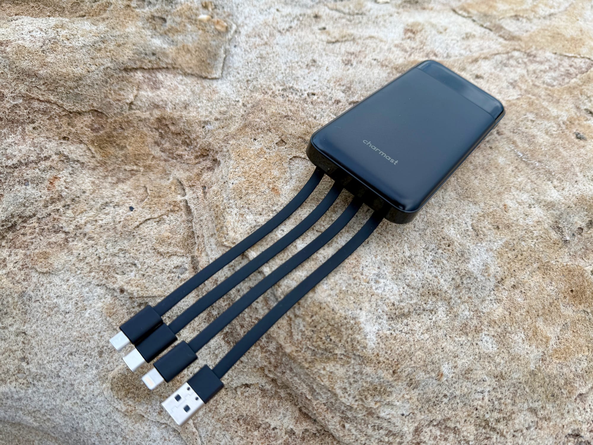 Charmast 10,000mAh power bank with its four built-in cables fanned out on a rock