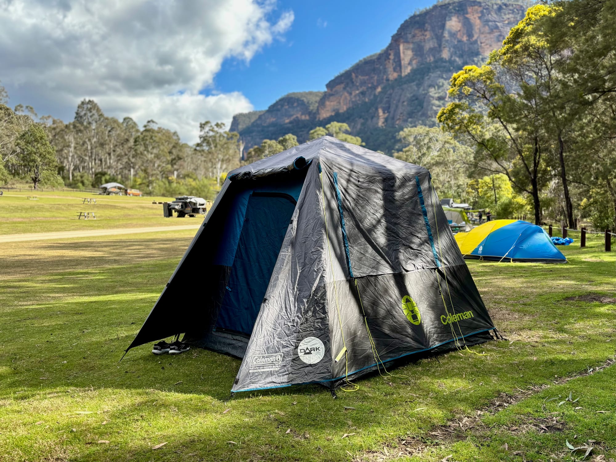 The Coleman Instant Up 4P Darkroom tent set up on a grassy campsite at Coorongooba, below tall sandstone cliffs
