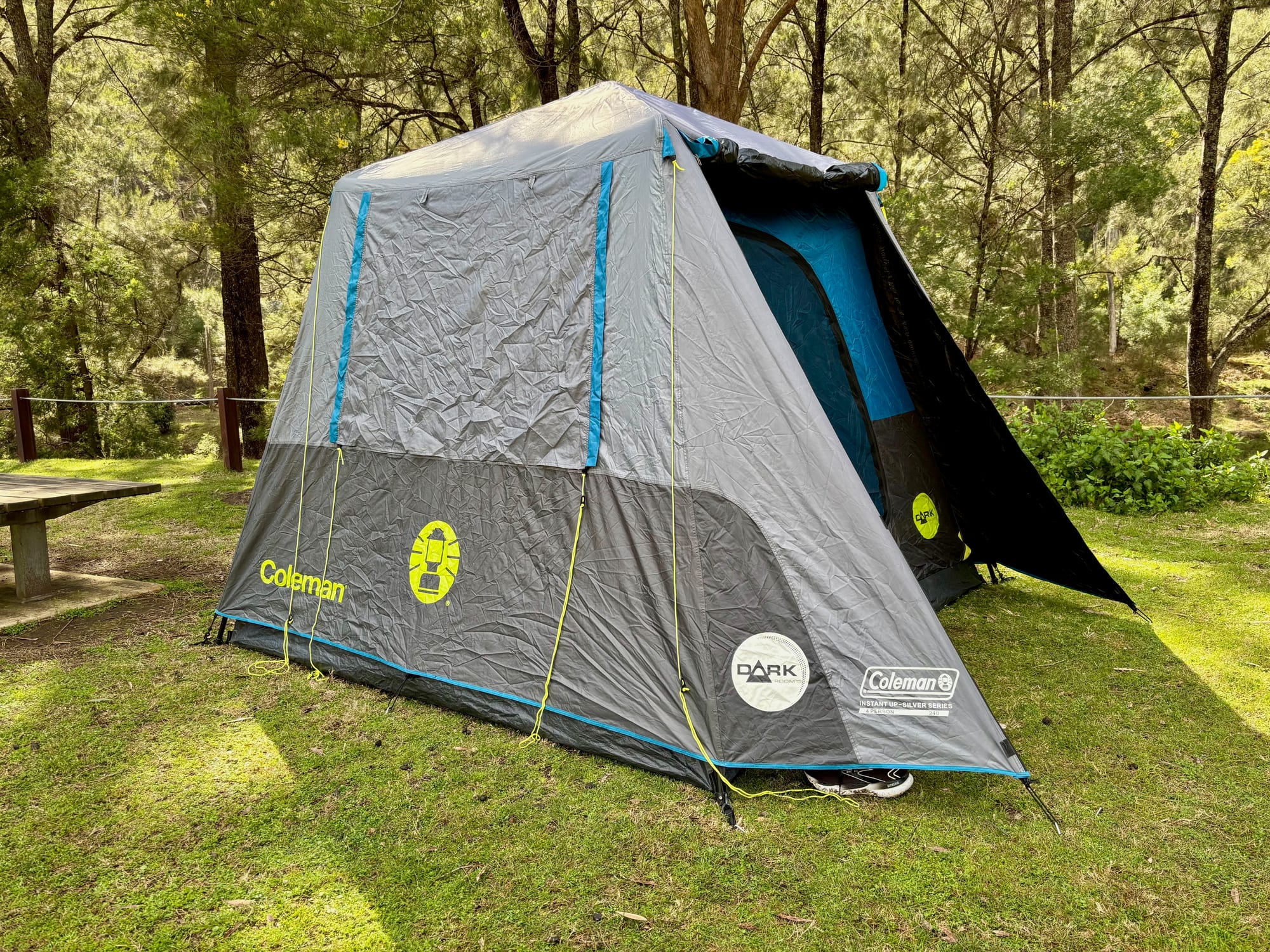 The side and back of the Coleman Instant Up tent, with the front panel staked out beside the door