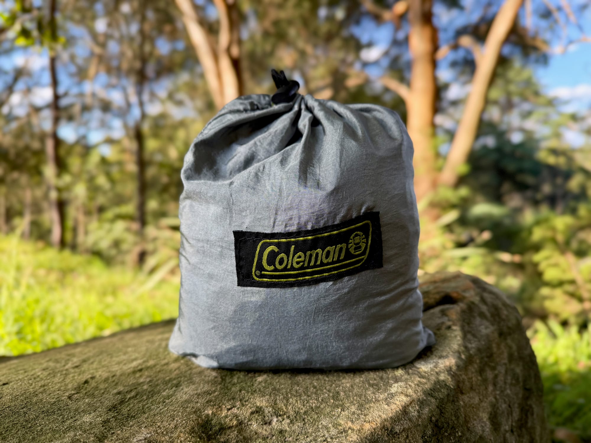 The Coleman Lightweight Sling Hammock packed into its grey pocket on a rock