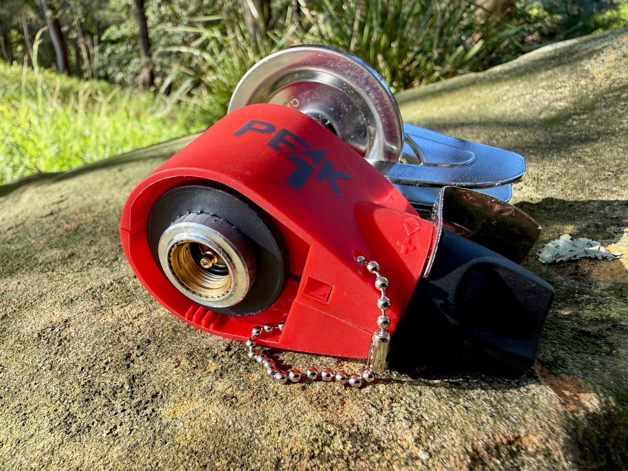 The folded Coleman Peak 1 stove showing the brass thread that screws onto the canister